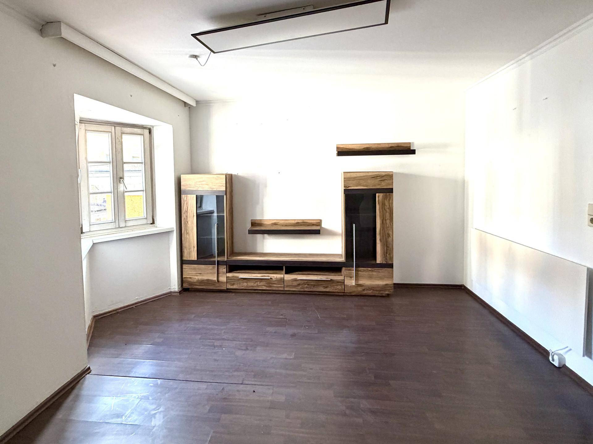 Helles Wohnzimmer mit dunklem Laminatboden und moderner Holz-Medienkonsole, bereit zur individuellen Gestaltung.