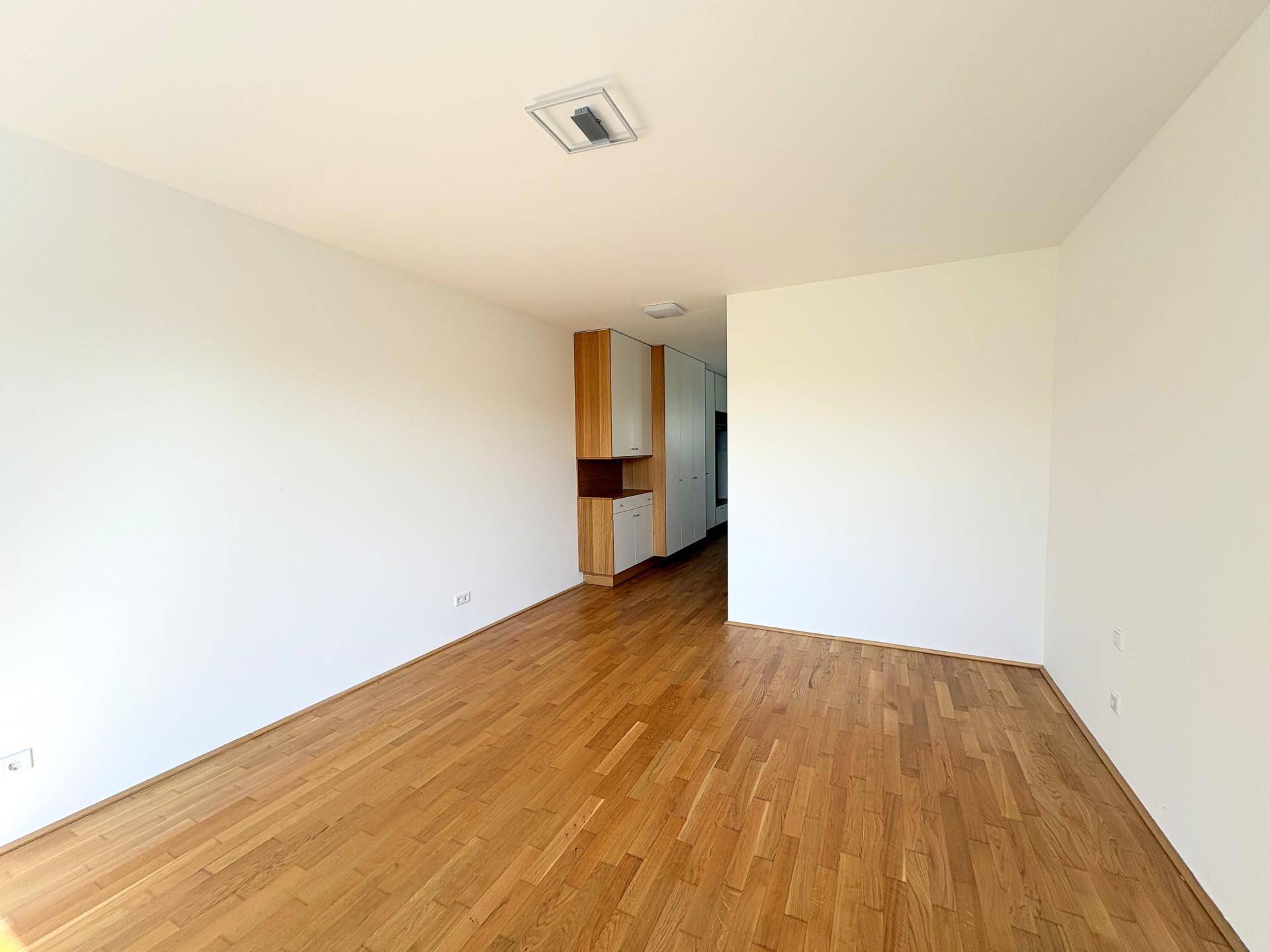 Geräumiger, heller Wohnbereich mit Parkettboden und integrierten Schränken im Hintergrund.