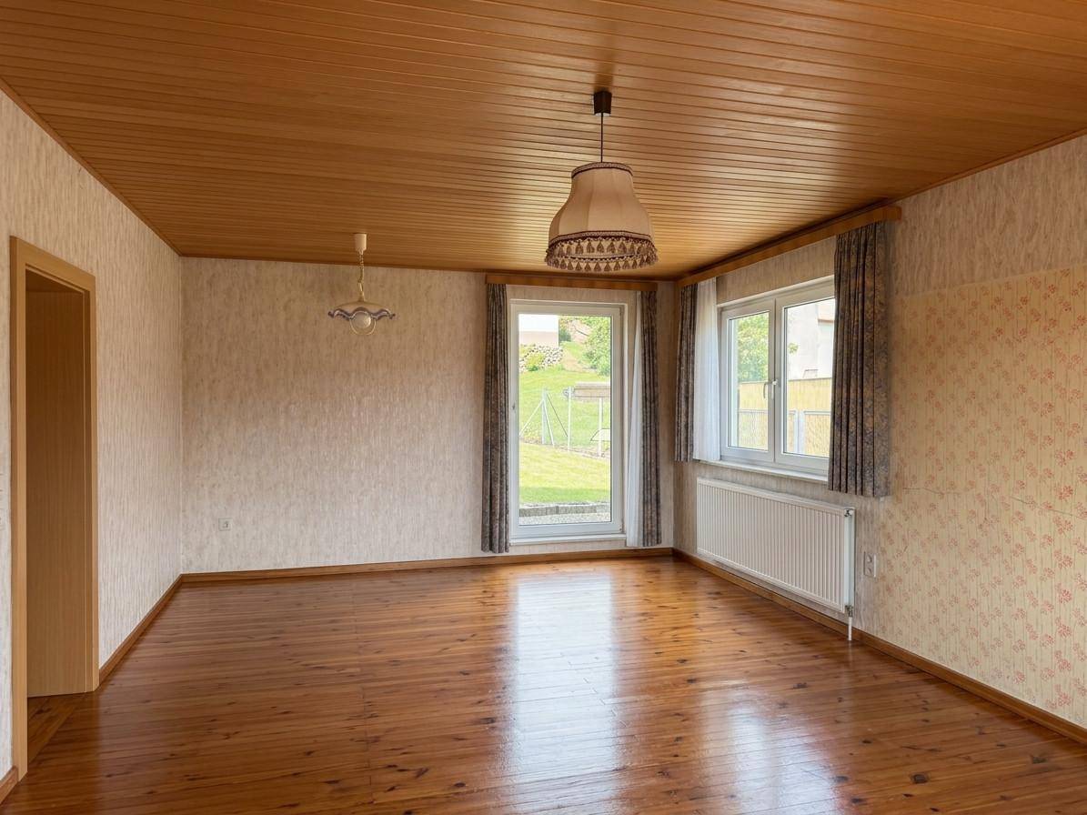 Geräumiger Raum mit Holzboden, Holzdecke und Zugang zum Garten, ideal für einen Wohnbereich.