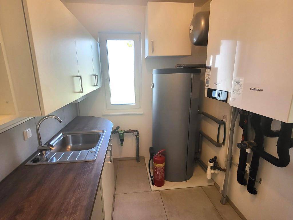 Praktischer Hauswirtschaftsraum mit Spülbecken, Warmwasserspeicher und Heizungsanlage.