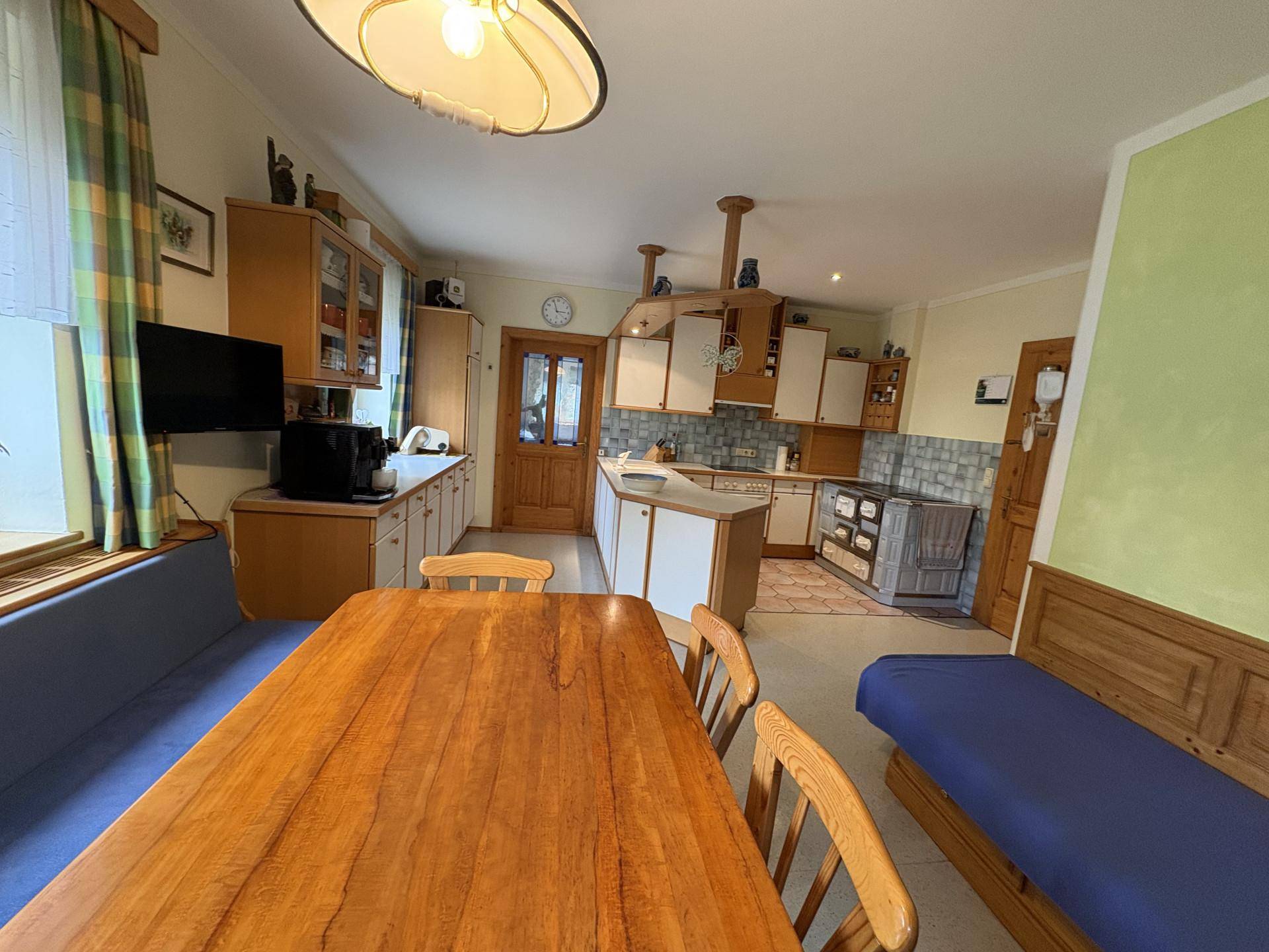 Gemütliche Wohnküche mit Holztisch, Sitzbank und traditionellem Holzofen, ideal für Familien.