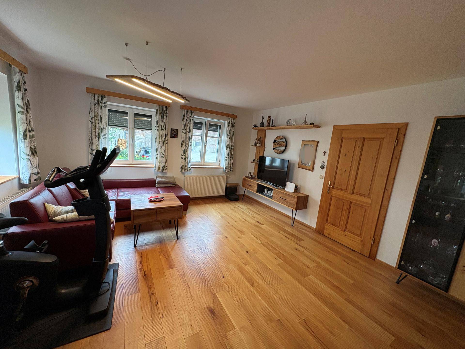Helles Wohnzimmer mit Holzboden, rotem Sofa und modernen Möbeln, bietet vielseitige Nutzung.
