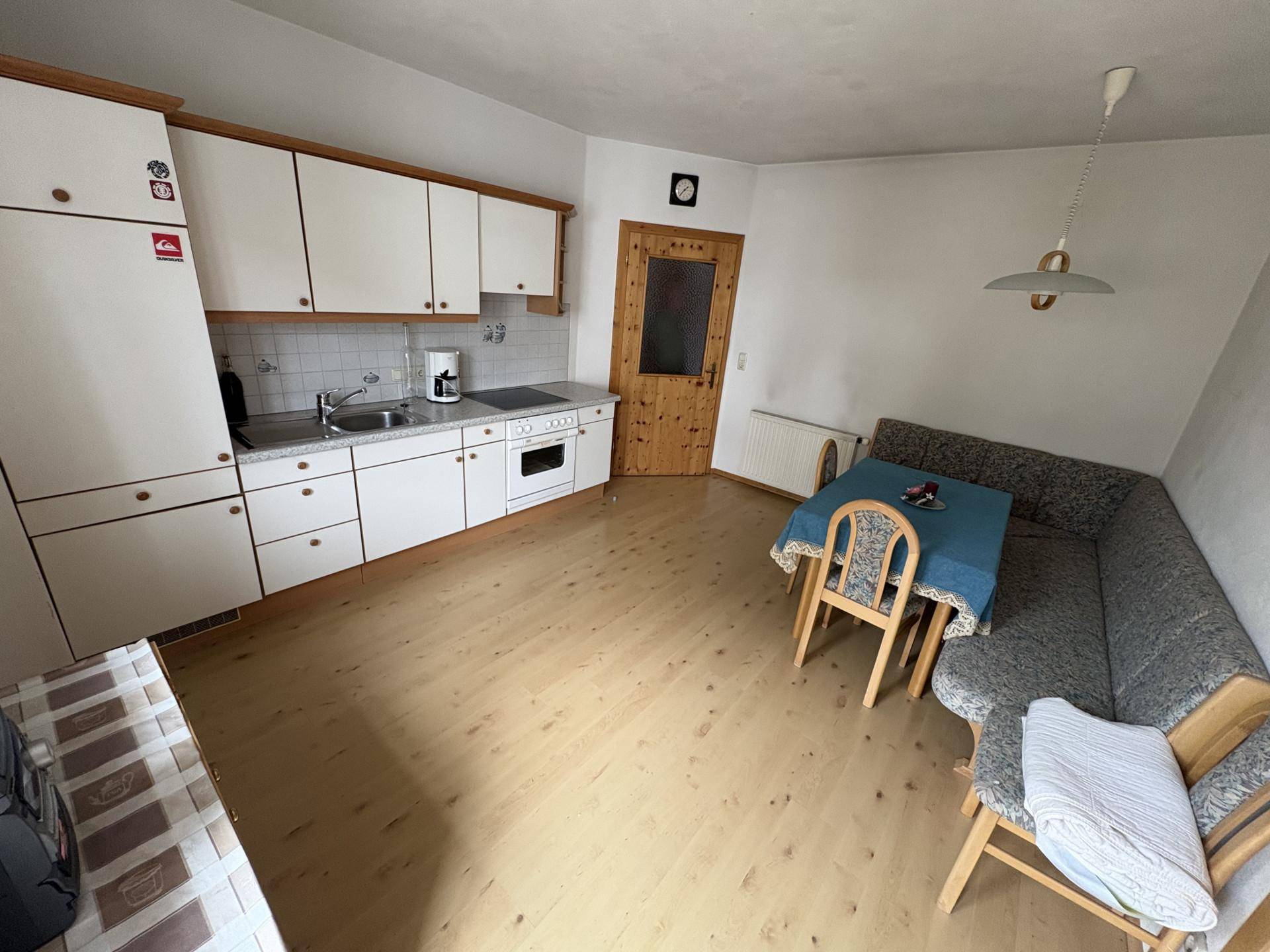 Kleine Küche mit Essbereich, weißen Schränken und hellem Holzboden, praktisch eingerichtet.