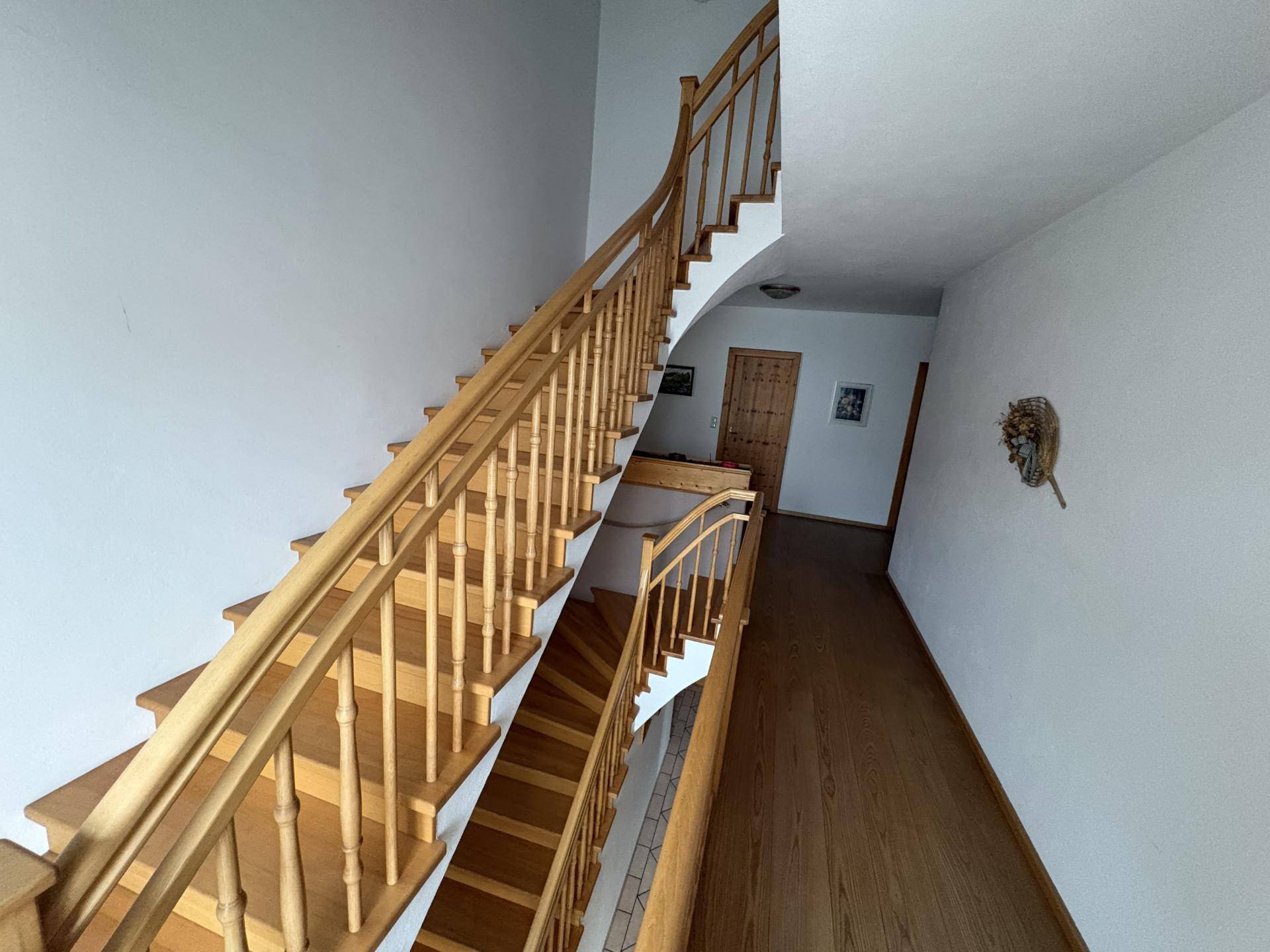 Heller Flur mit eleganter Holztreppe, die die verschiedenen Etagen des Hauses verbindet.