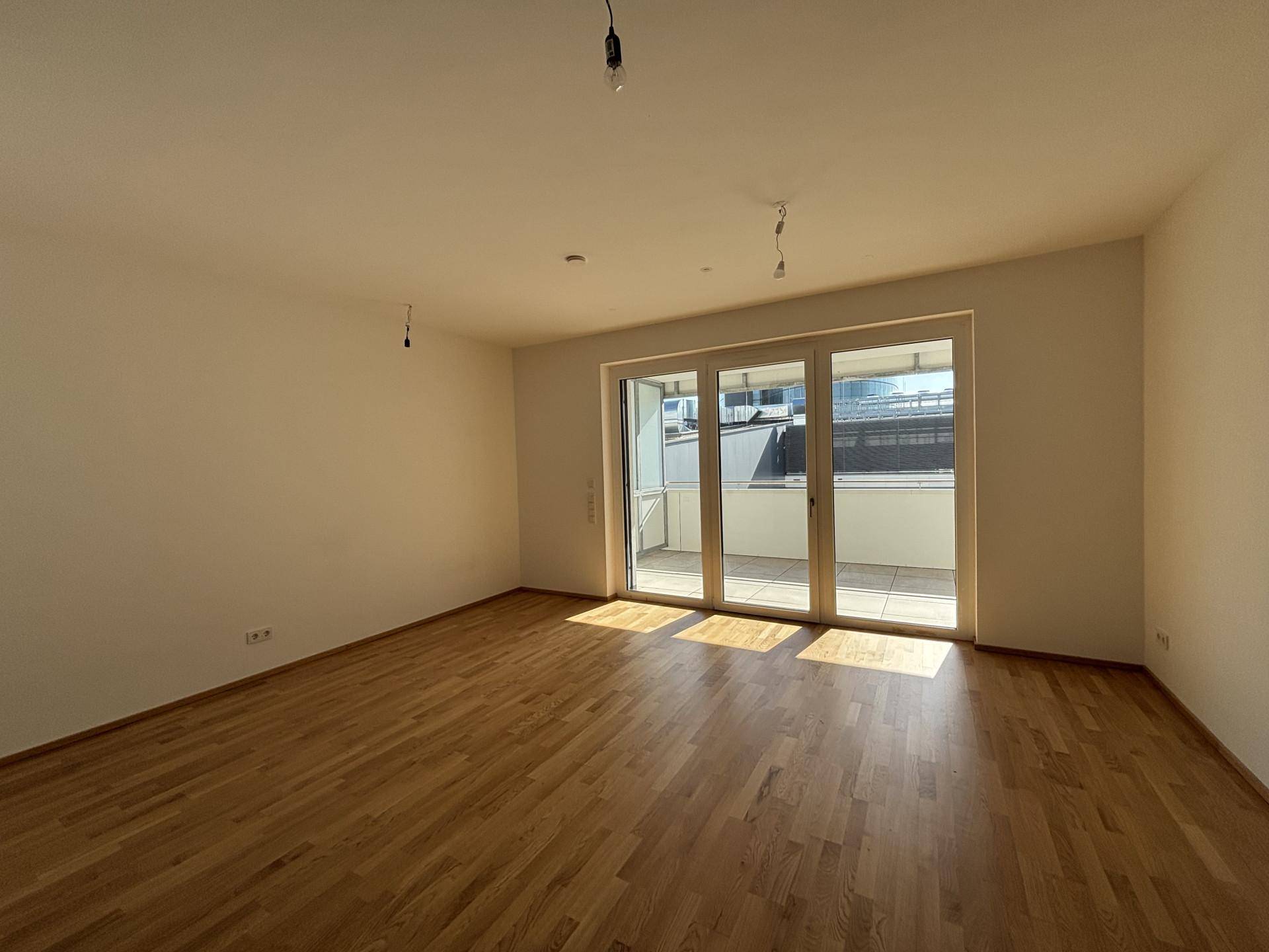 Heller Wohnbereich mit Zugang zum Balkon und hochwertigem Parkettboden.