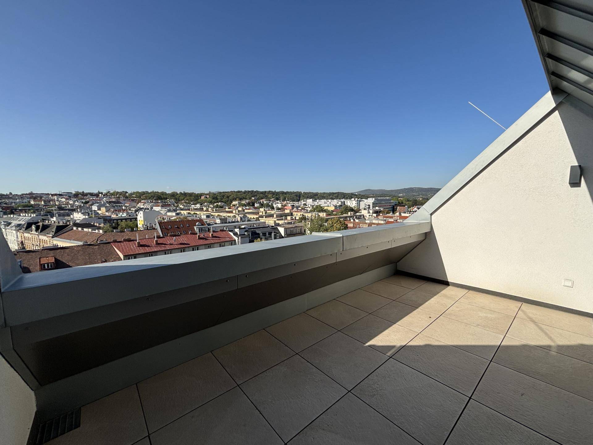 Weitläufige Terrasse mit Panoramablick über die Dächer der Stadt an einem sonnigen Tag.