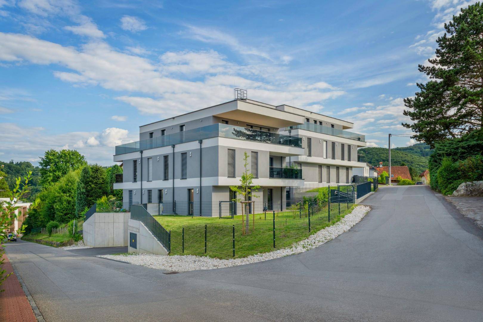 Modernes Mehrfamilienhaus mit klarer Architektur und großzügigen Balkonen in grüner Umgebung.