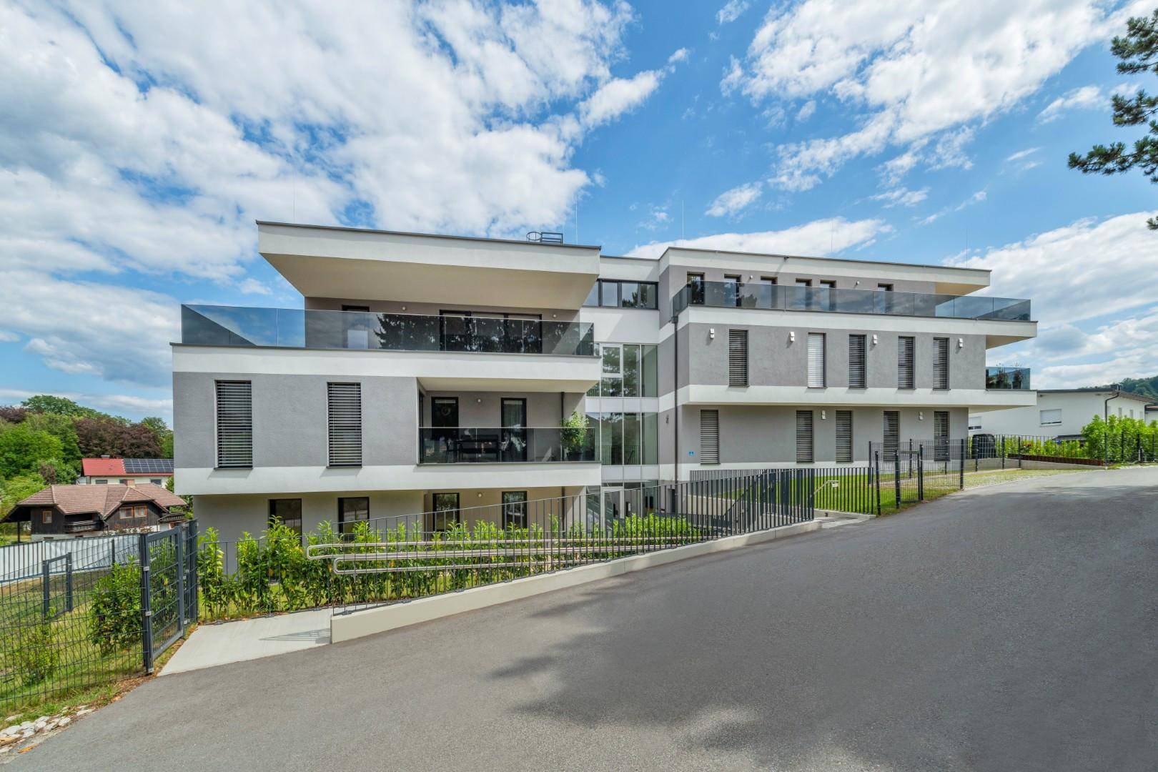 Elegantes Mehrfamilienhaus mit moderner Fassade und barrierefreiem Zugang über eine Rampe.