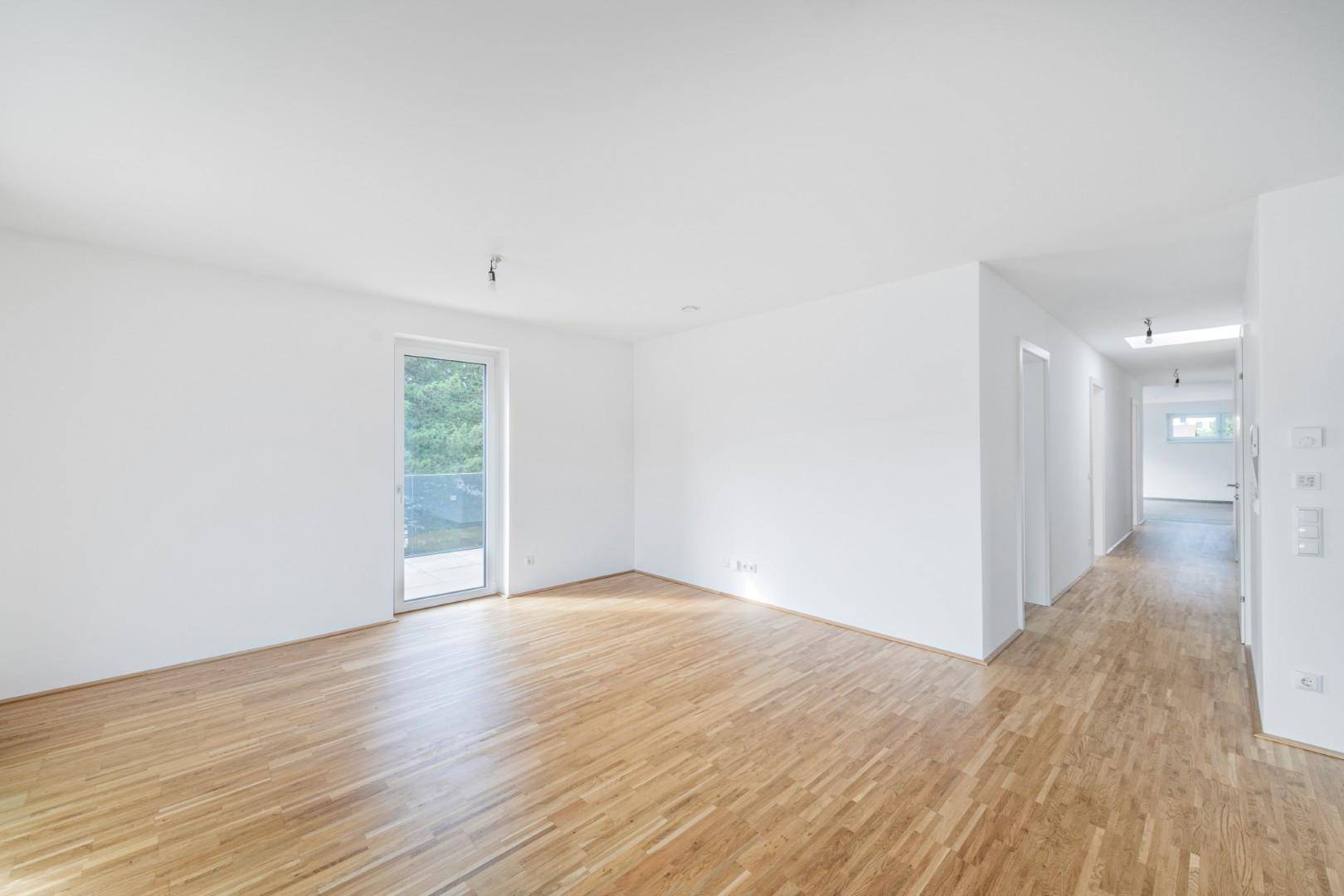 Lichtdurchfluteter Raum mit Holzboden und Zugang zu einem kleinen Balkon, ideal als Schlaf- oder Wohnzimmer.
