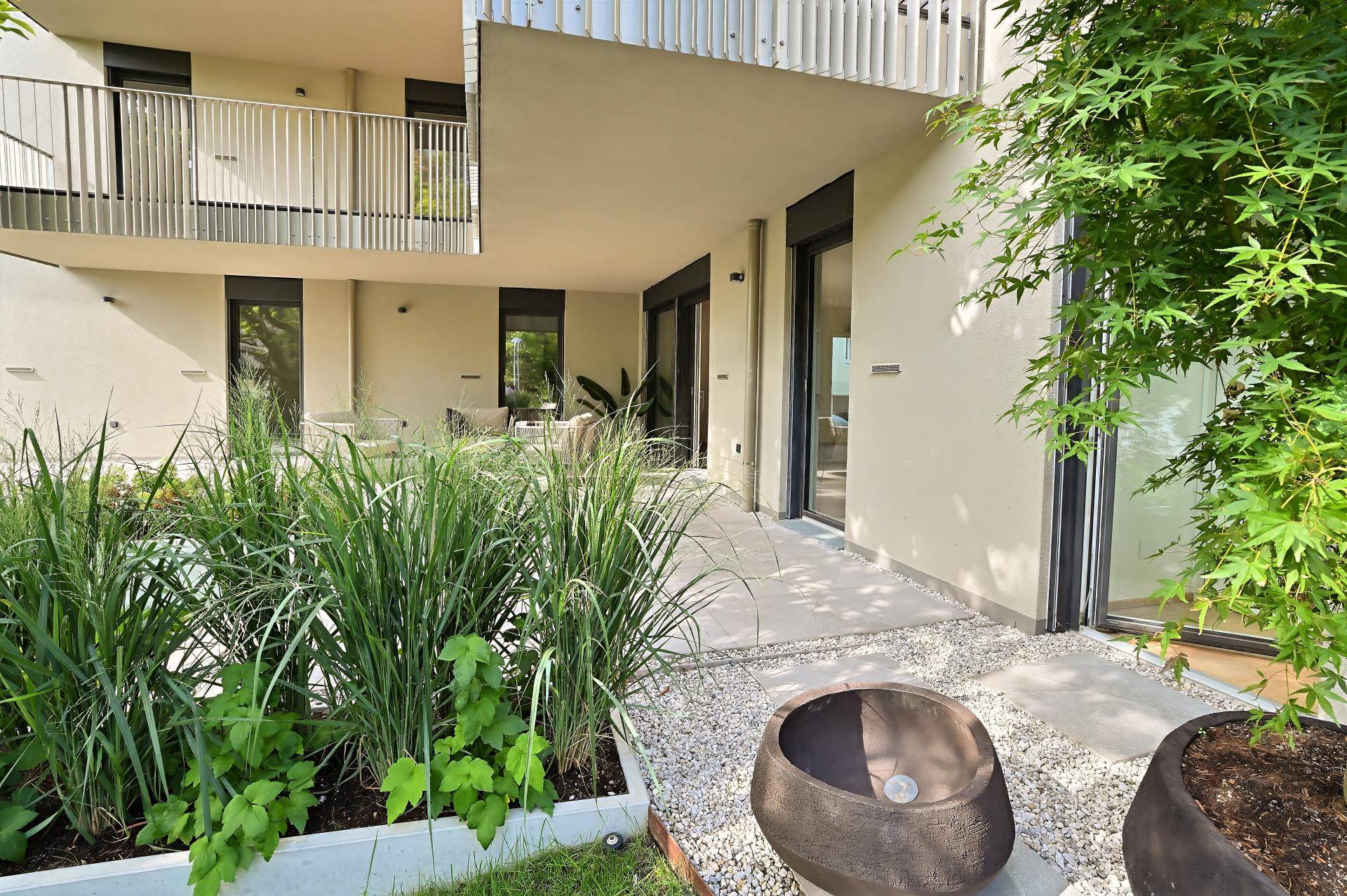 Moderne Terrasse mit Kiesbeet und Pflanzen, die zum Gartenbereich des Gebäudes führt.