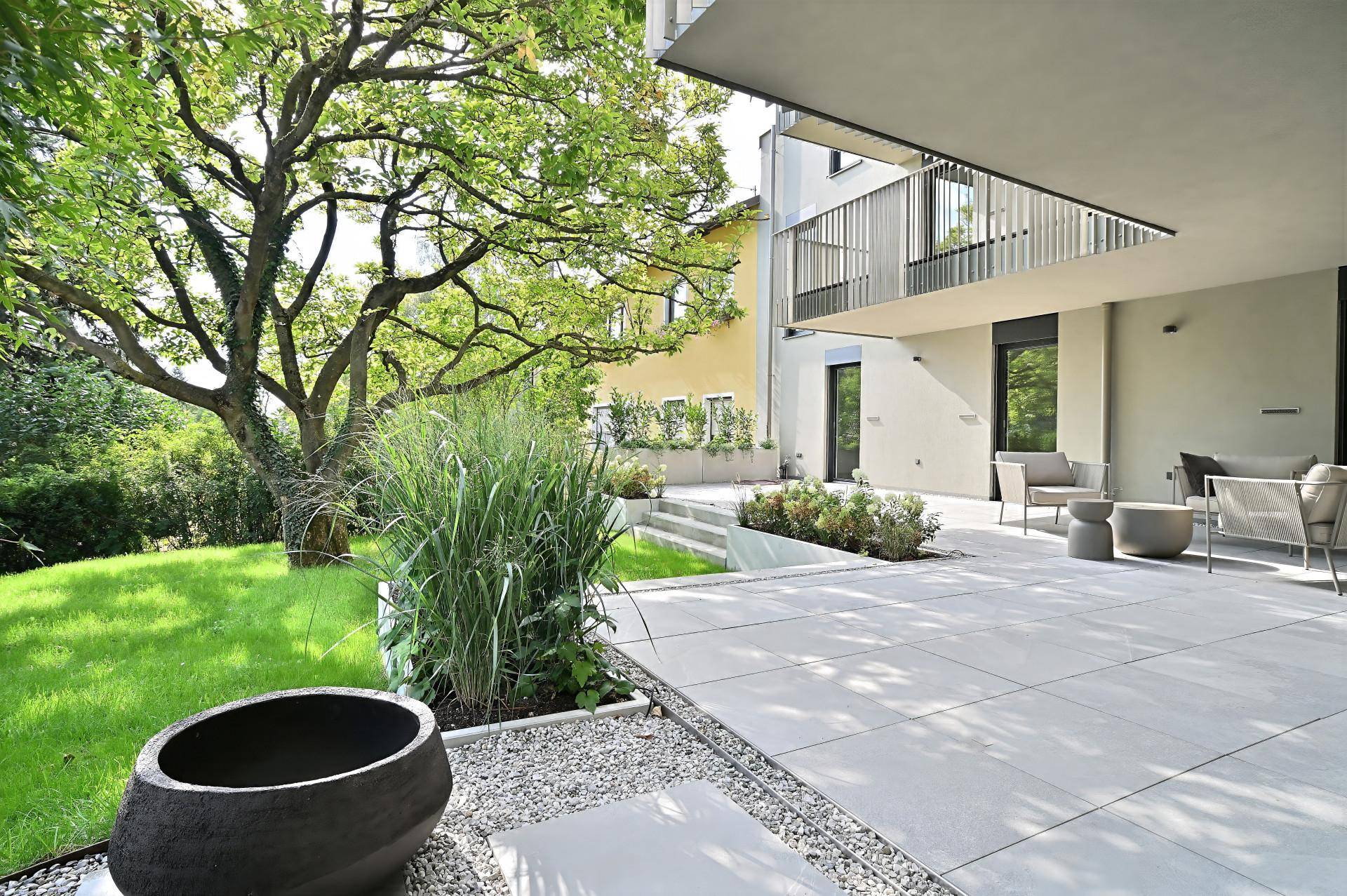 Großzügige Terrasse mit angrenzendem Garten und altem Baumbestand, umgeben von Natur.