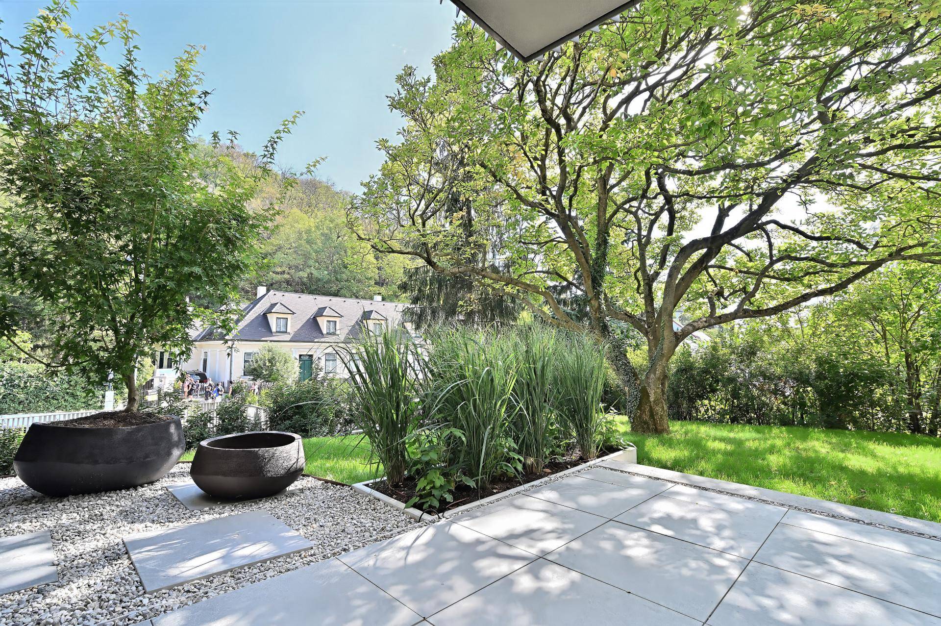 Geräumige Terrasse mit Kiesbeet und Rasenfläche, bietet einen schönen Blick auf die grüne Umgebung.