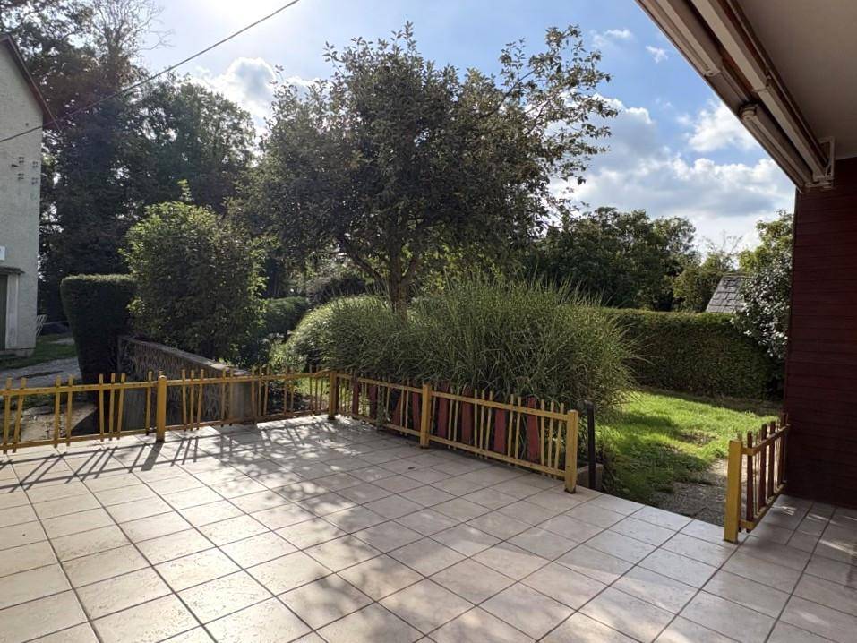 Geflieste Terrasse mit geländer und Blick auf den grünen Garten und die umliegende Natur.