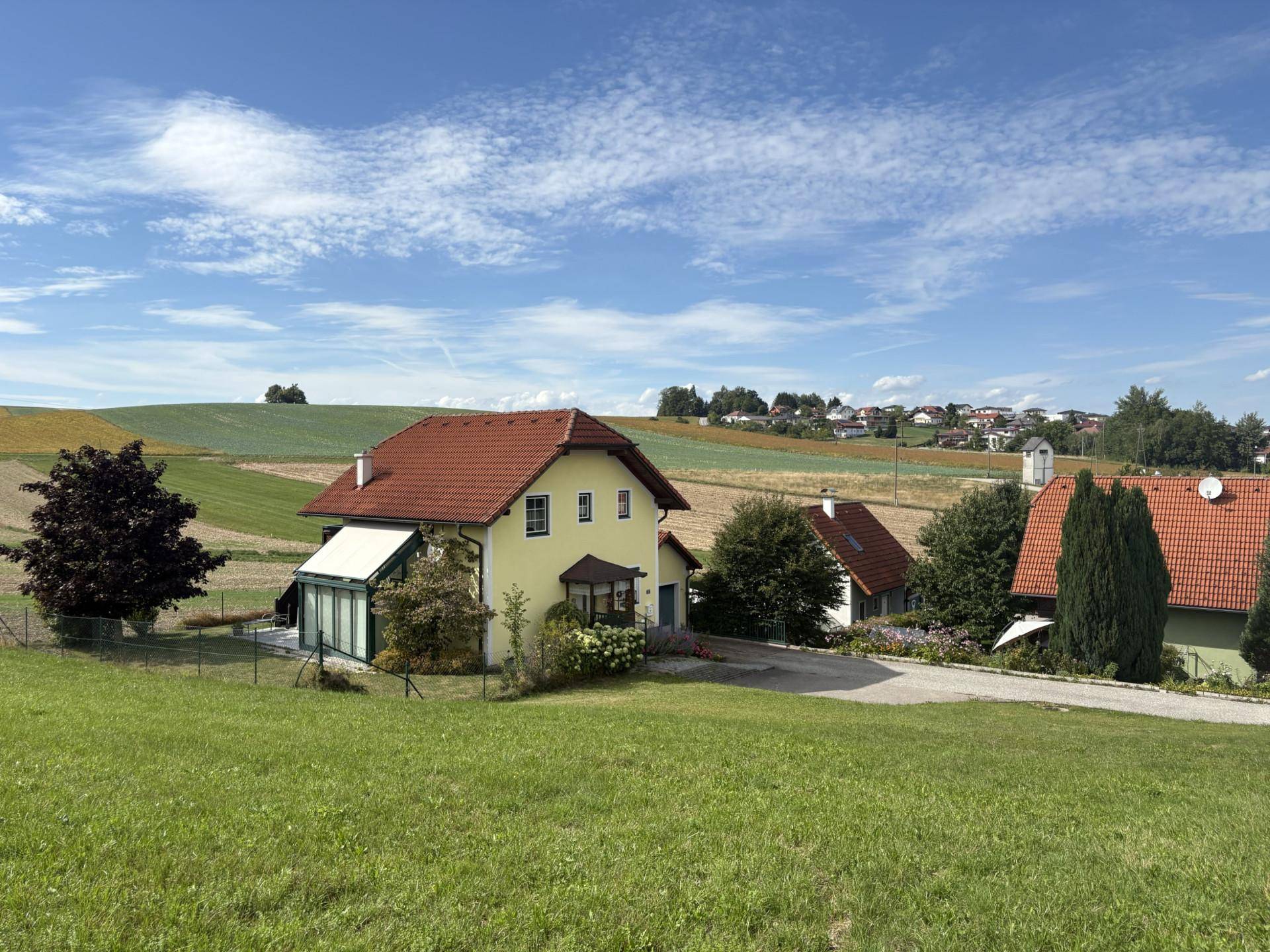 Einfamilienhaus in ländlicher Umgebung mit weiten Feldern und blauem Himmel.