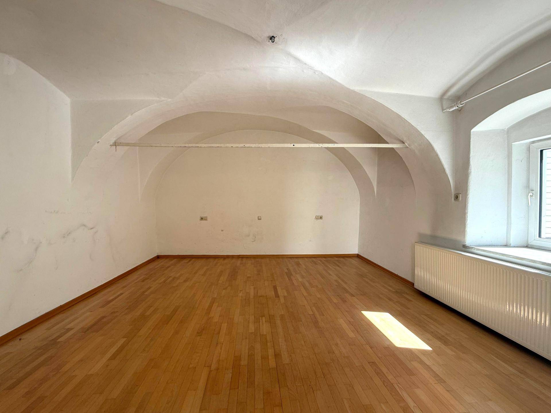 Raum mit beeindruckender Gewölbedecke, Holzboden und einem Fenster, ideal für kreative Nutzung.