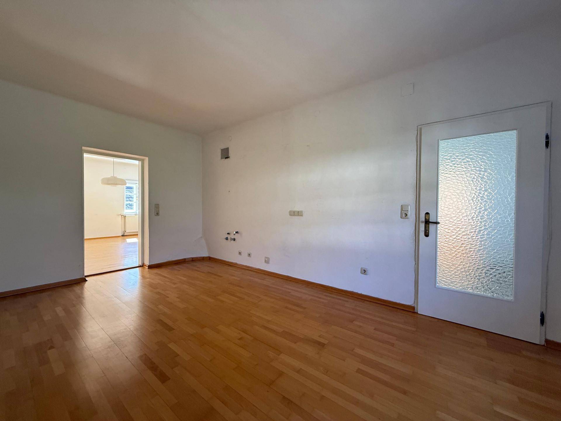 Heller Flur mit Holzboden und einer Tür mit strukturiertem Glas, die zu einem weiteren Raum führt.