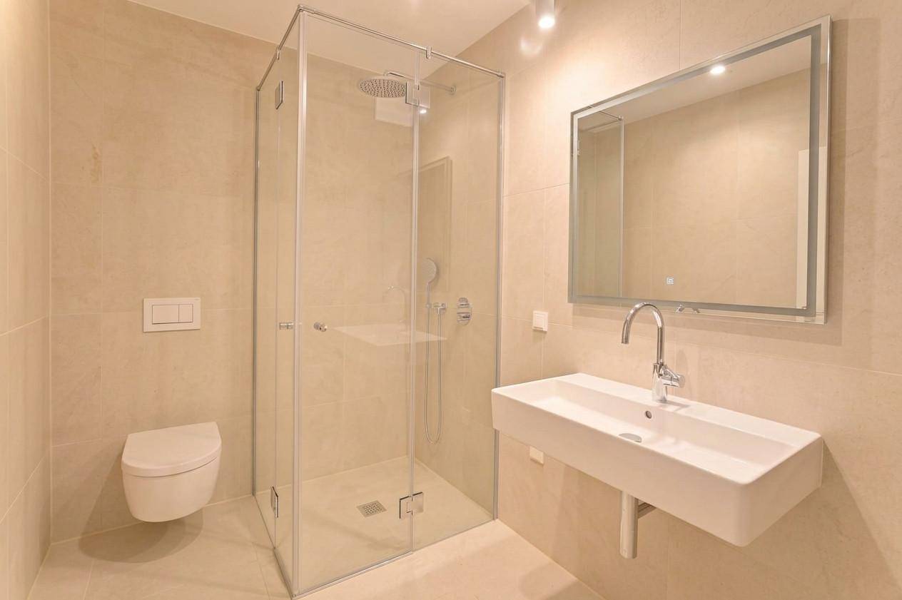 Modernes Badezimmer mit begehbarer Dusche, wandhängendem WC und Spiegel über dem Waschbecken.