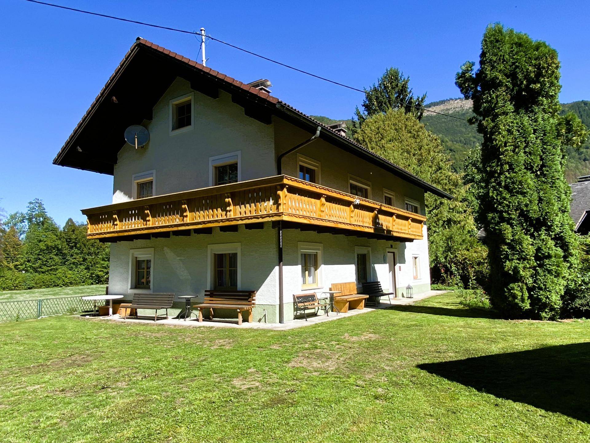 Traditionelles Haus mit Holzbalkon und großem Garten in ländlicher Umgebung.