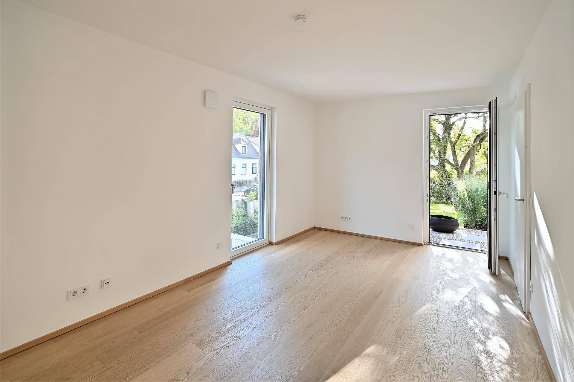 Geräumiges Zimmer mit Holzboden und zwei Zugängen zum Außenbereich, vielseitig nutzbar.