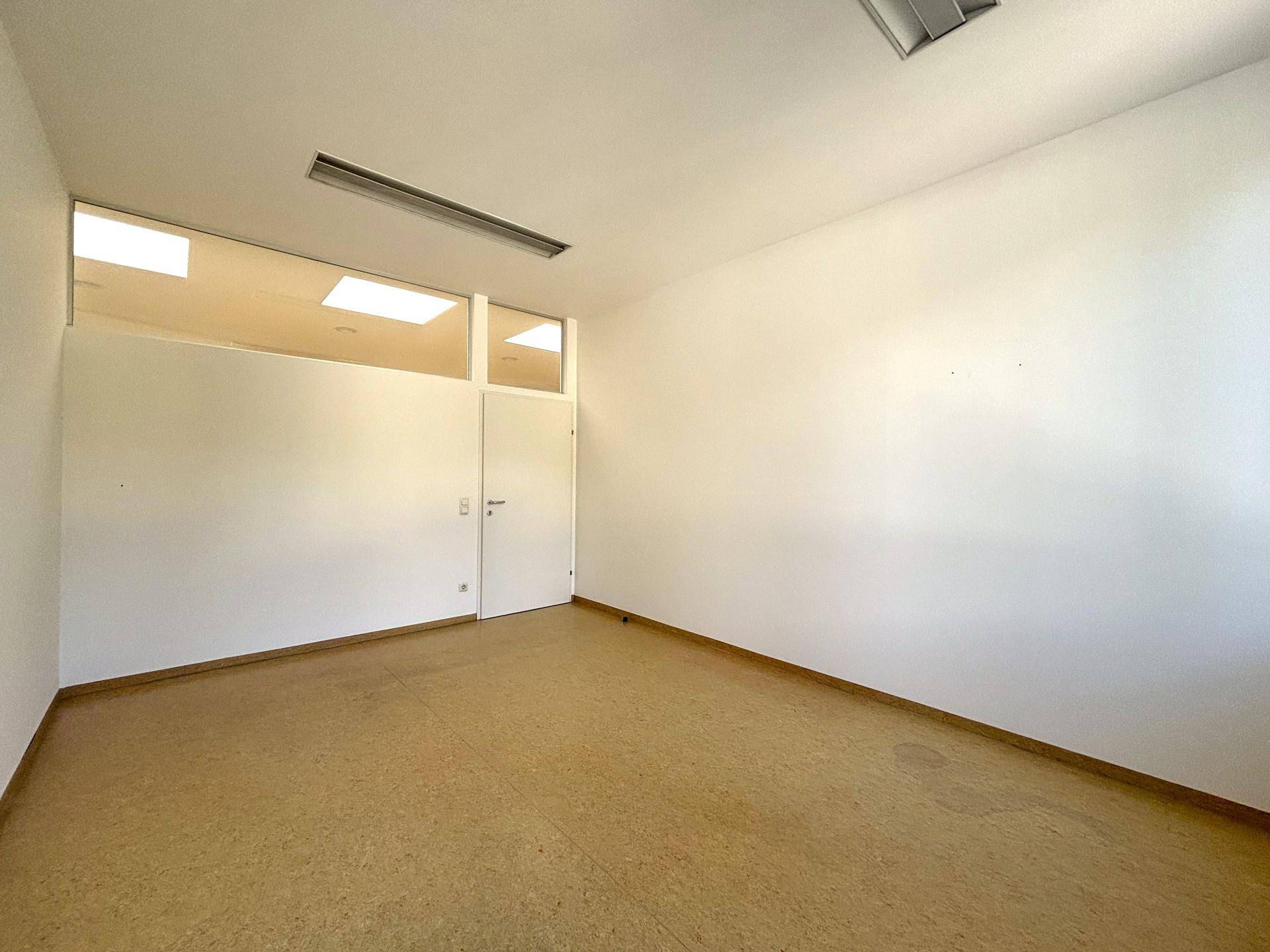 Büroraum mit Linoleumboden und einer Trennwand mit Oberlicht, die für zusätzliche Helligkeit sorgt.