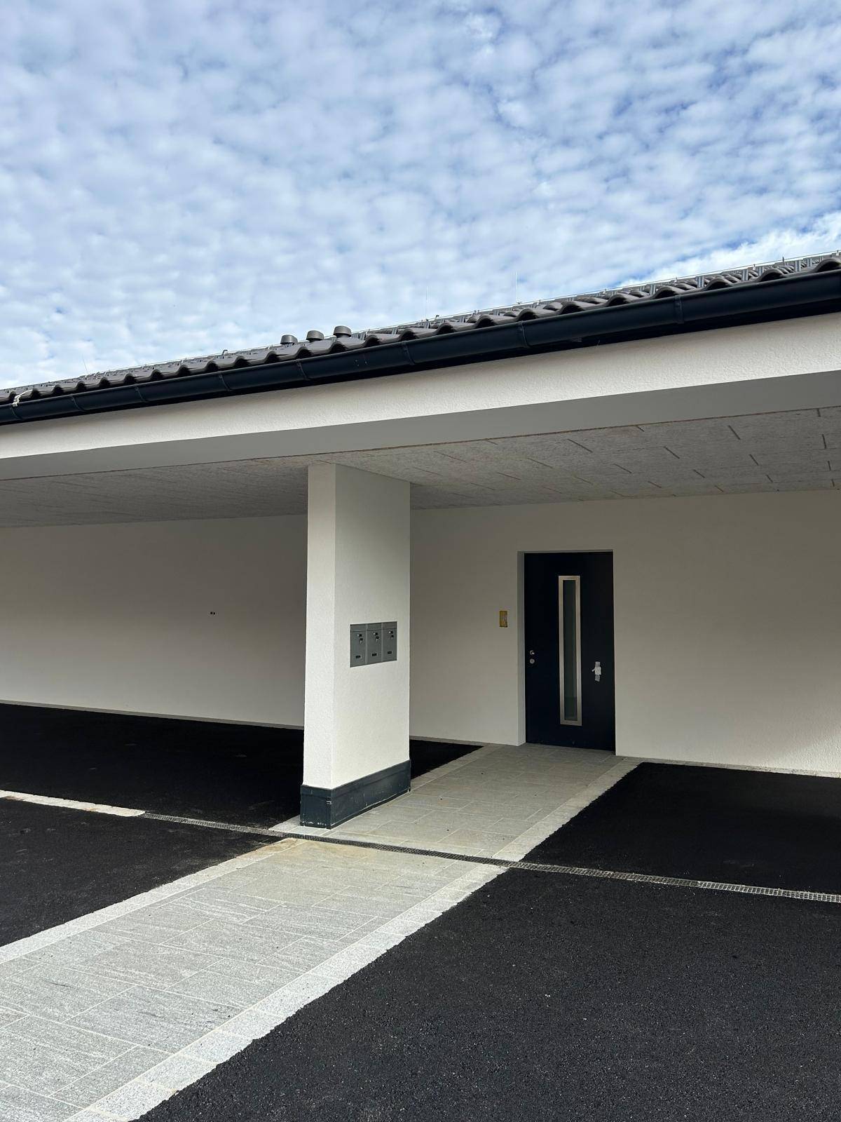 Eingangsbereich unter dem Carport mit moderner Haustür und Briefkästen.