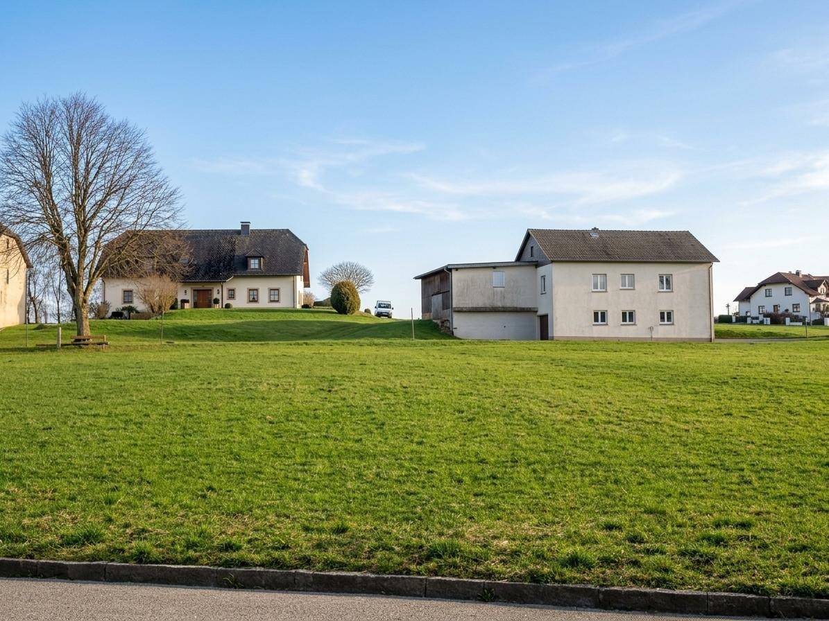 Zwei Wohnhäuser in einer weiten ländlichen Landschaft mit großen grünen Feldern im Vordergrund.