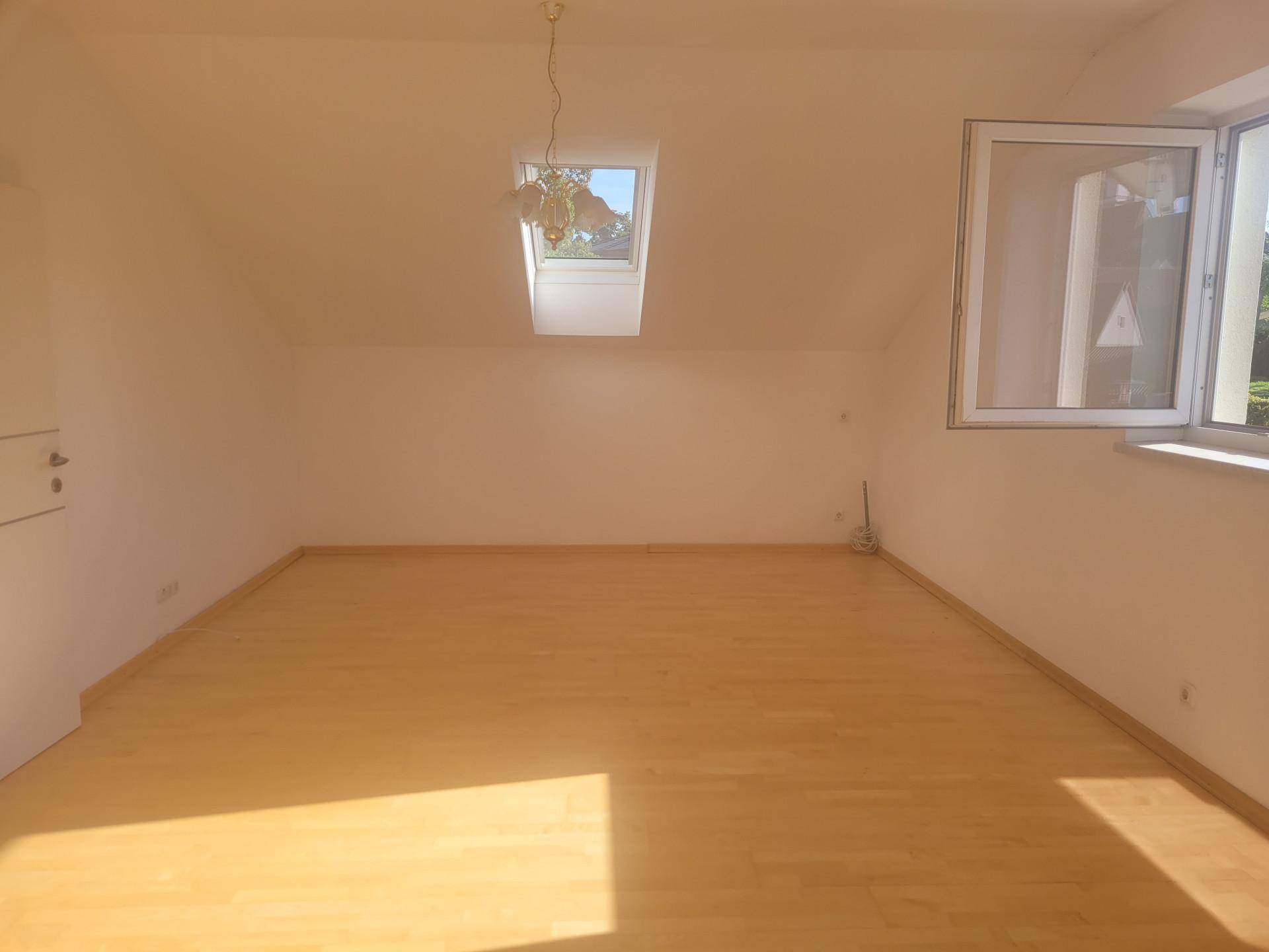 Heller Dachraum mit Schrägdecke, Dachfenster und zusätzlichem Seitenfenster.
