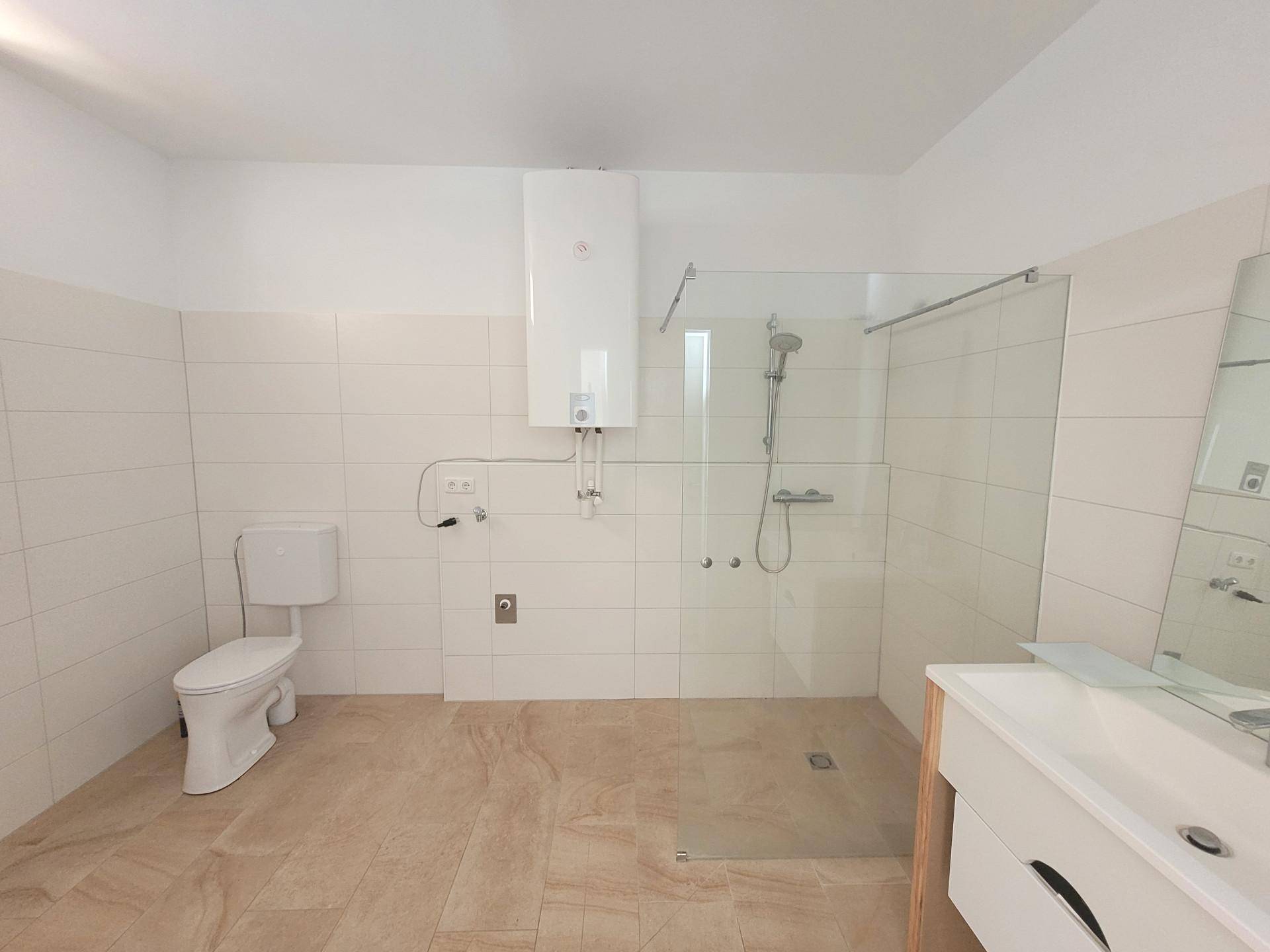 Modernes Badezimmer mit ebenerdiger Dusche, WC und Einzelwaschbecken.