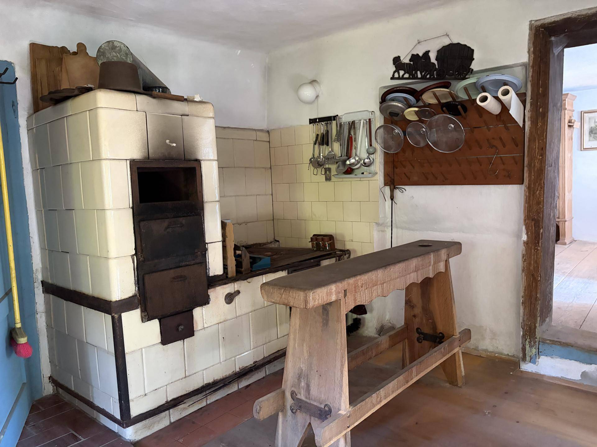 Traditionelle Küche mit Kachelofen, einfachen Fliesen und rustikalen Holzmöbeln.