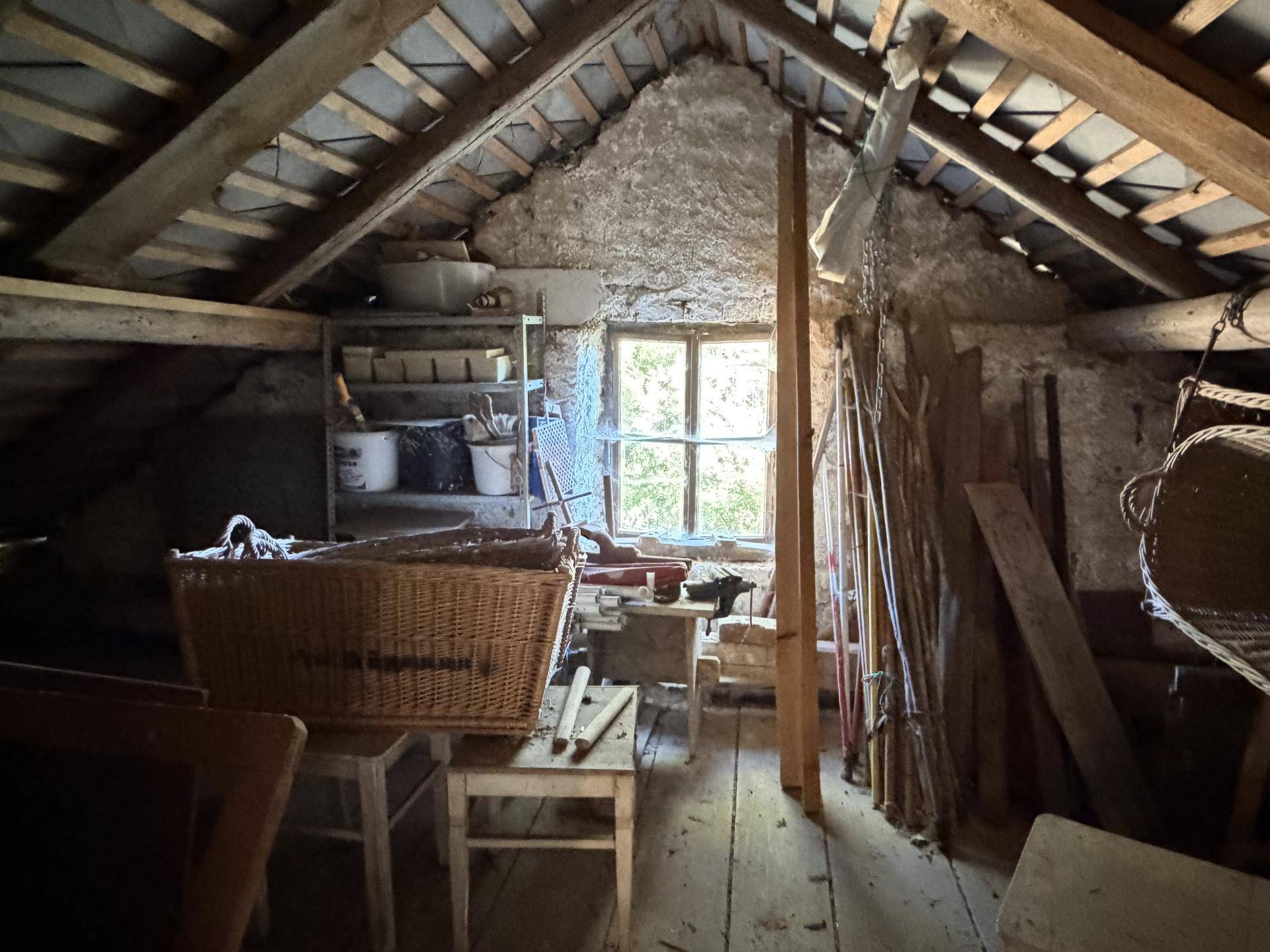 Dachboden mit Holzbalken, Fenster und Lagerfläche, in ursprünglichem Zustand.