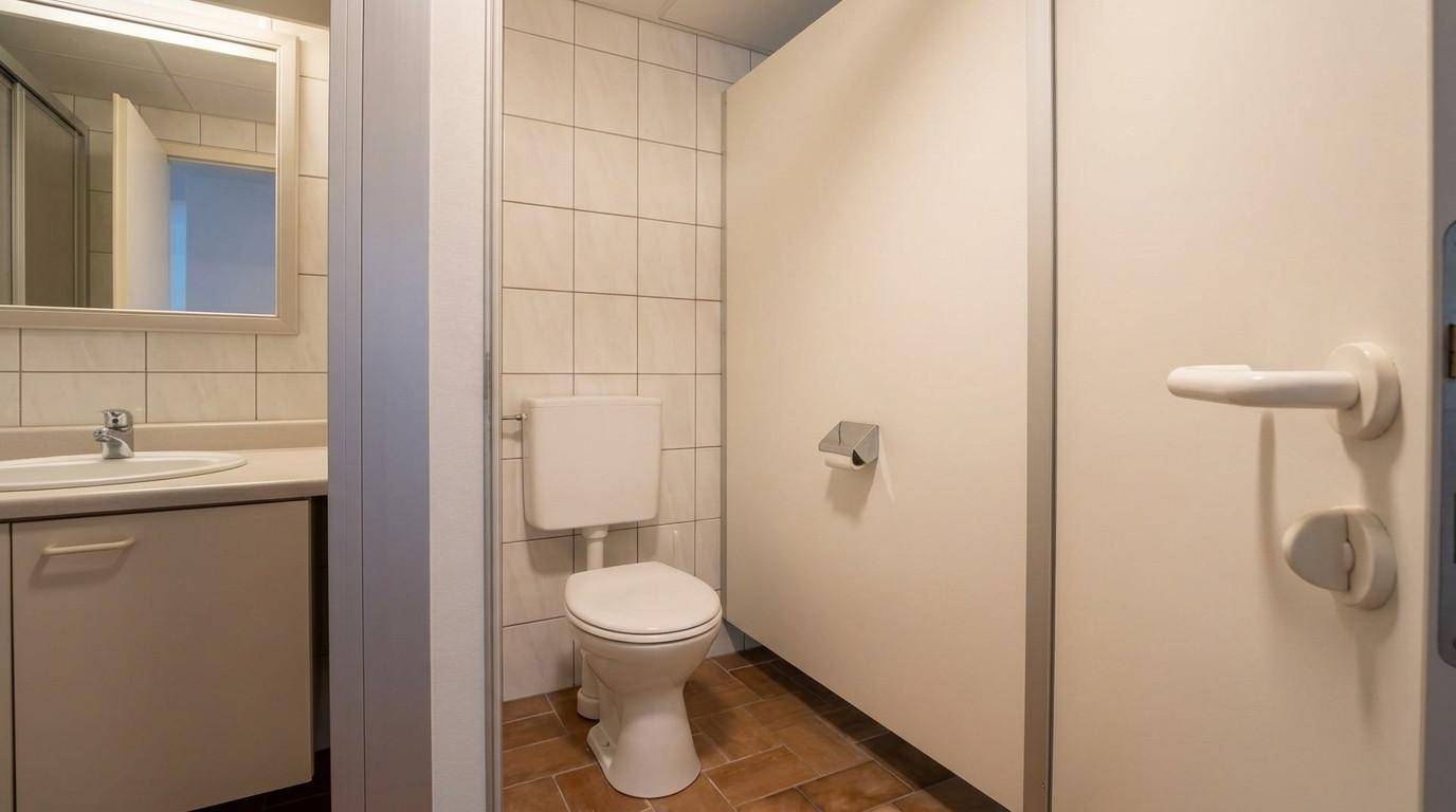 Kleines WC mit Toilette, Waschbecken und Spiegel, einfach gefliest.