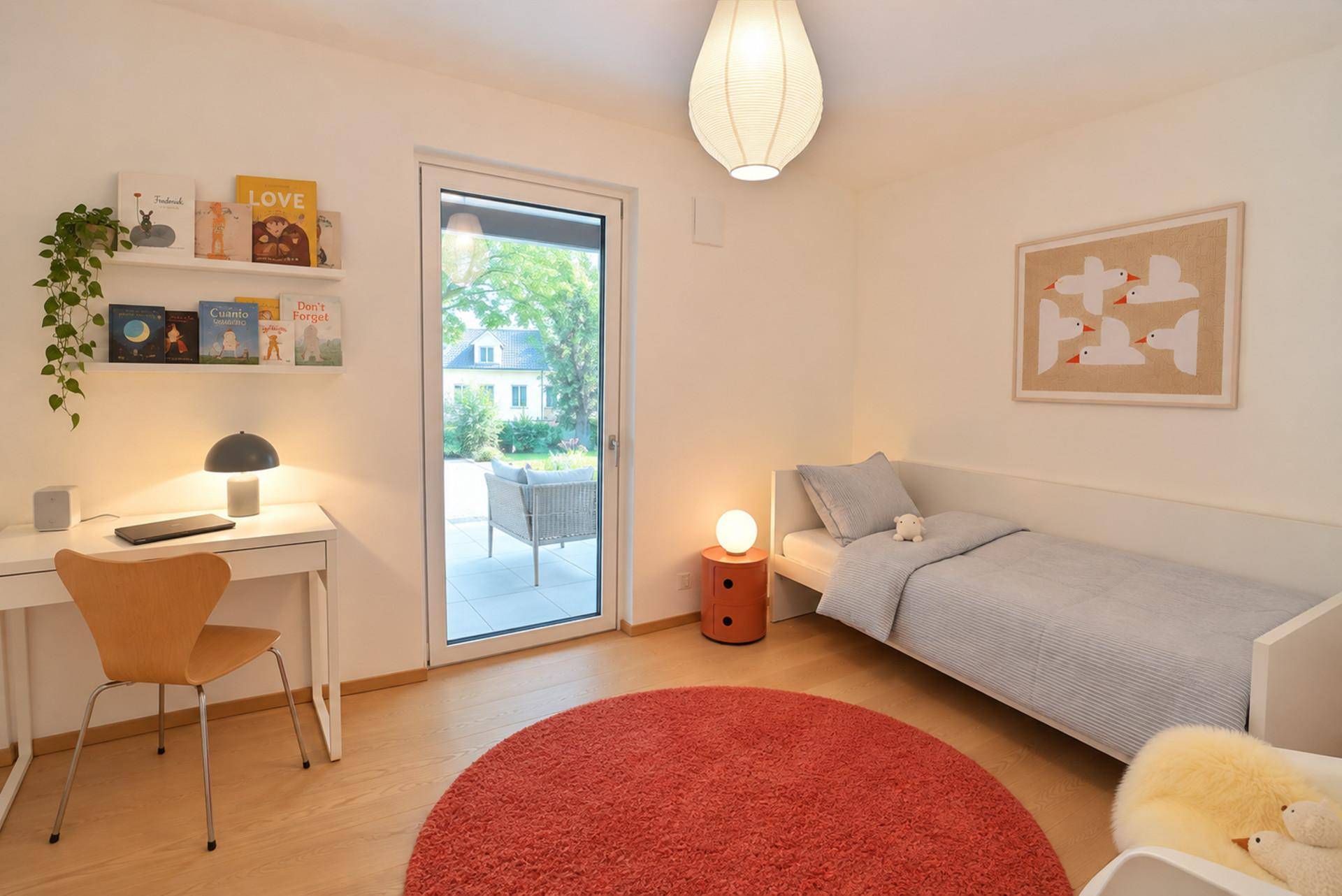 Helles Kinderzimmer mit Holzboden, Schreibtisch und Zugang zur Terrasse, gemütlich und funktional eingerichtet.