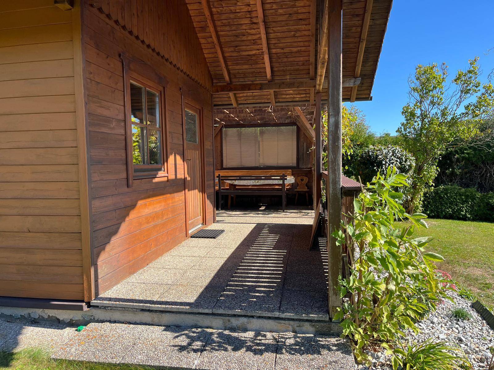 Überdachter Eingangsbereich mit Holzverkleidung und Zugang zum Garten.