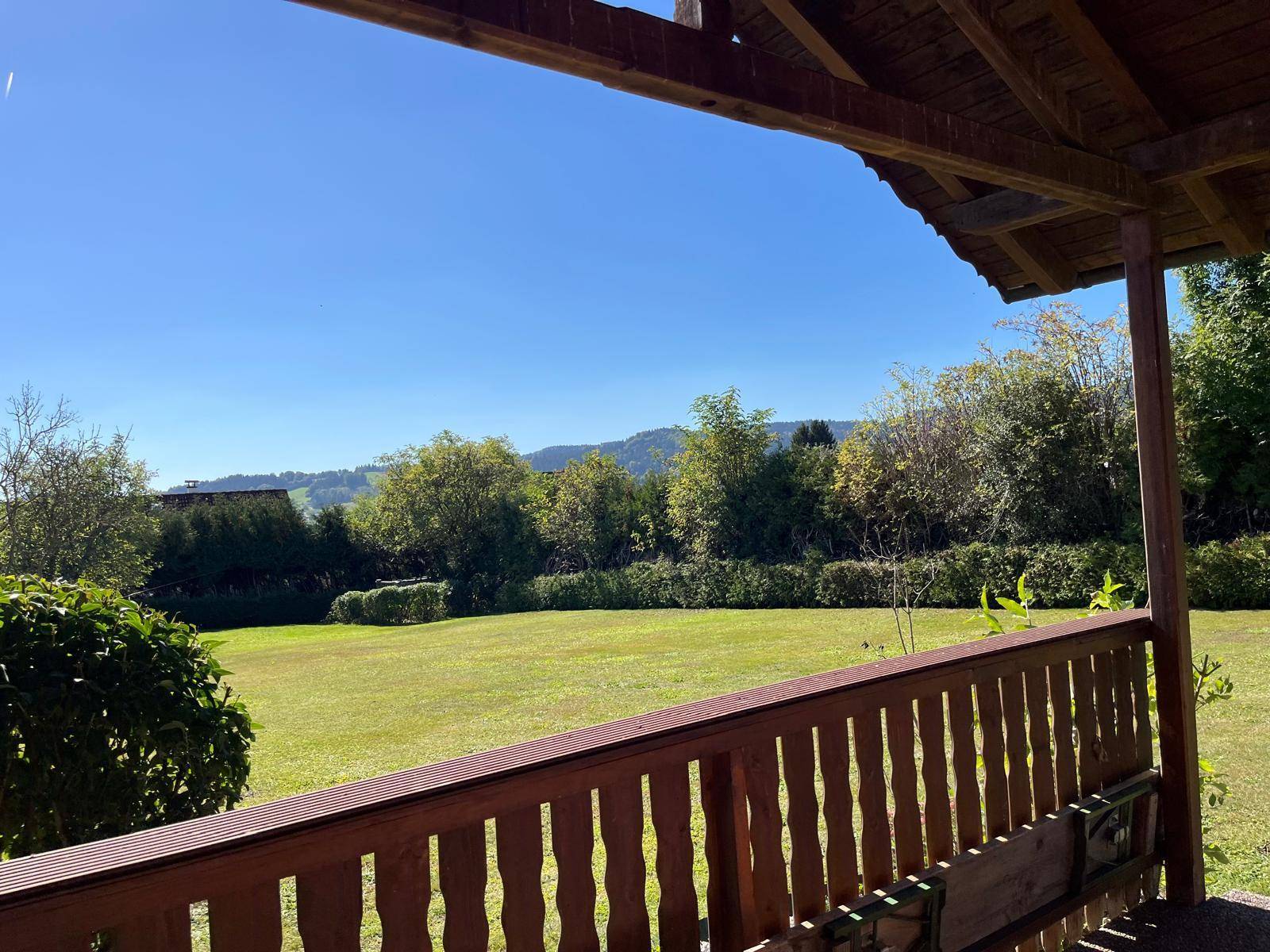 Weitblick vom überdachten Sitzbereich über den Garten und die grüne Landschaft.