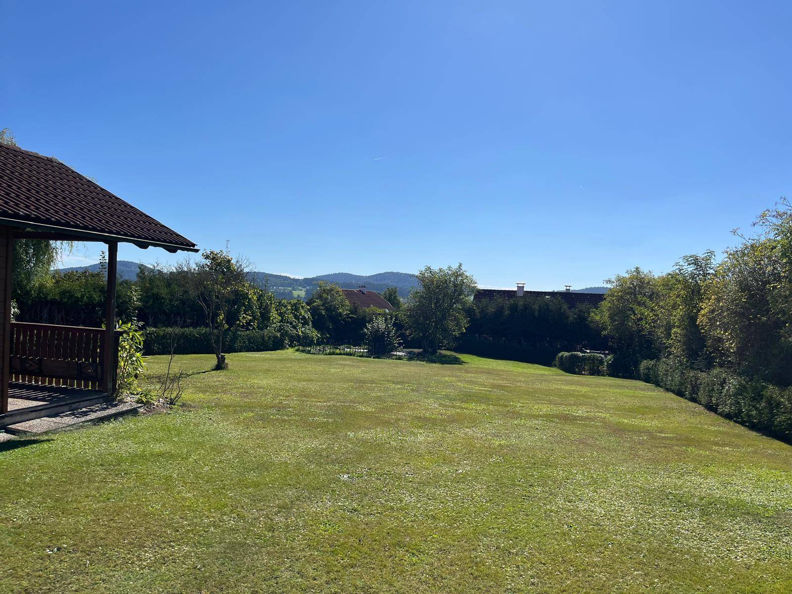 Weitläufiger grüner Garten mit Blick auf die umliegende Hügellandschaft und Berge.