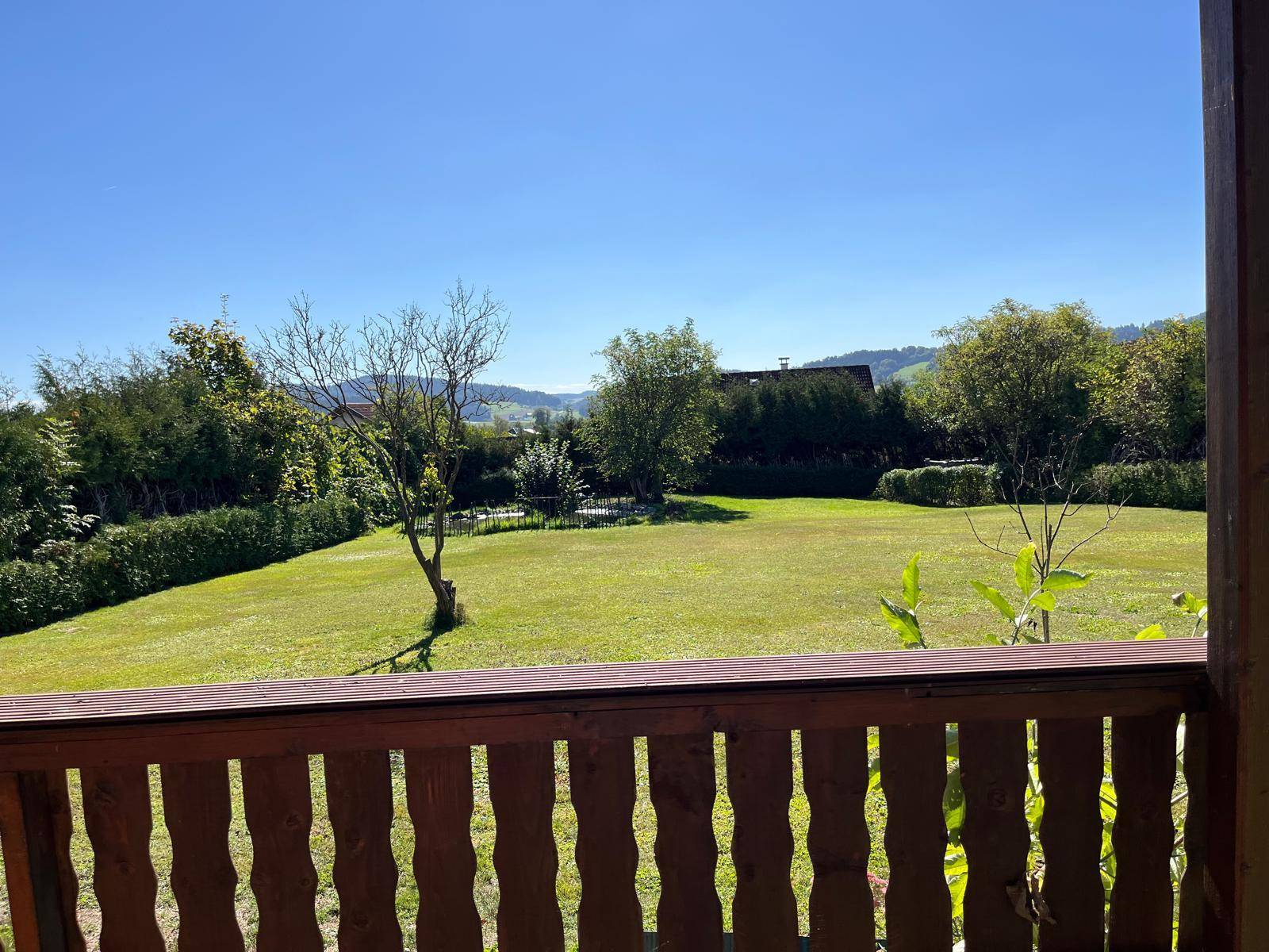 Panoramablick vom überdachten Außenbereich auf den weitläufigen Garten und die Natur.