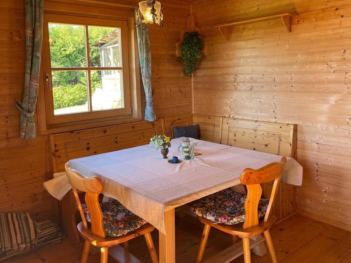 Heller Essbereich mit Holztisch, Eckbank und Blick ins Grüne durch das Fenster.