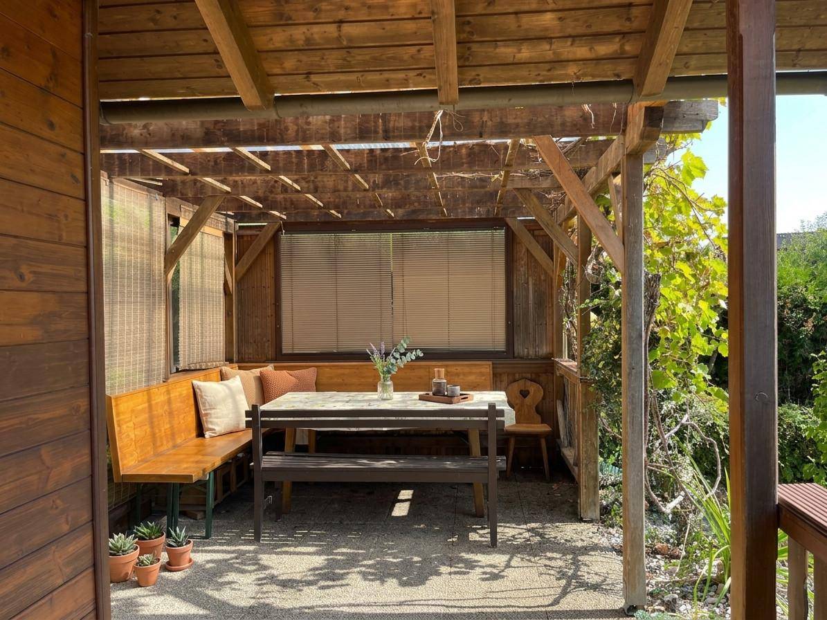 Überdachte Terrasse mit Holzbänken und Esstisch, ideal für Mahlzeiten im Freien.