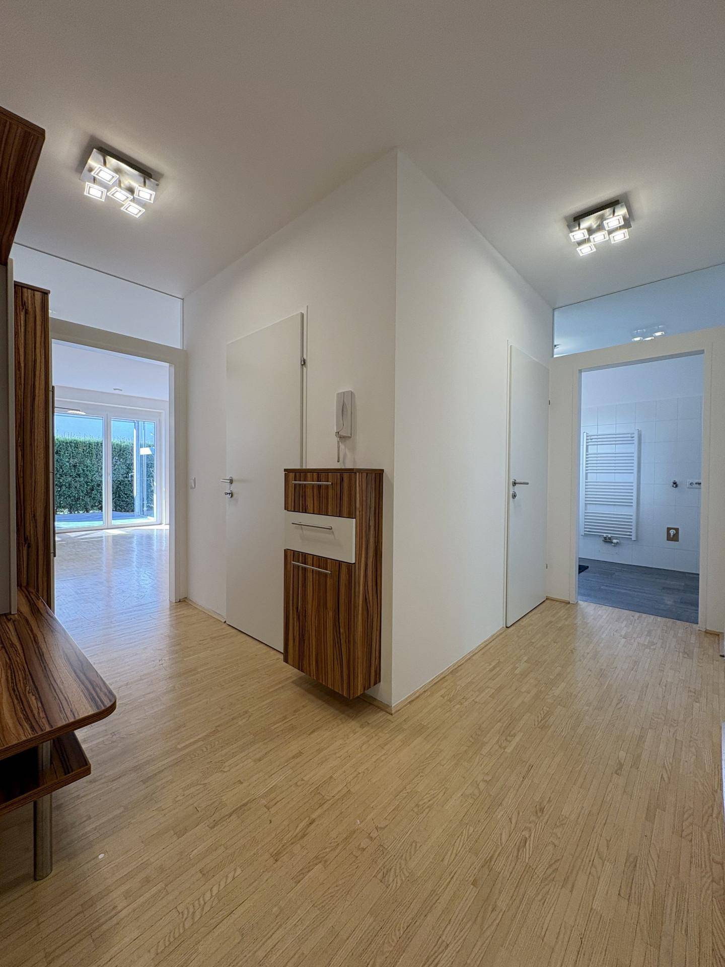 Heller Flur mit Holzboden und moderner Garderobe, der zu den verschiedenen Räumen führt.