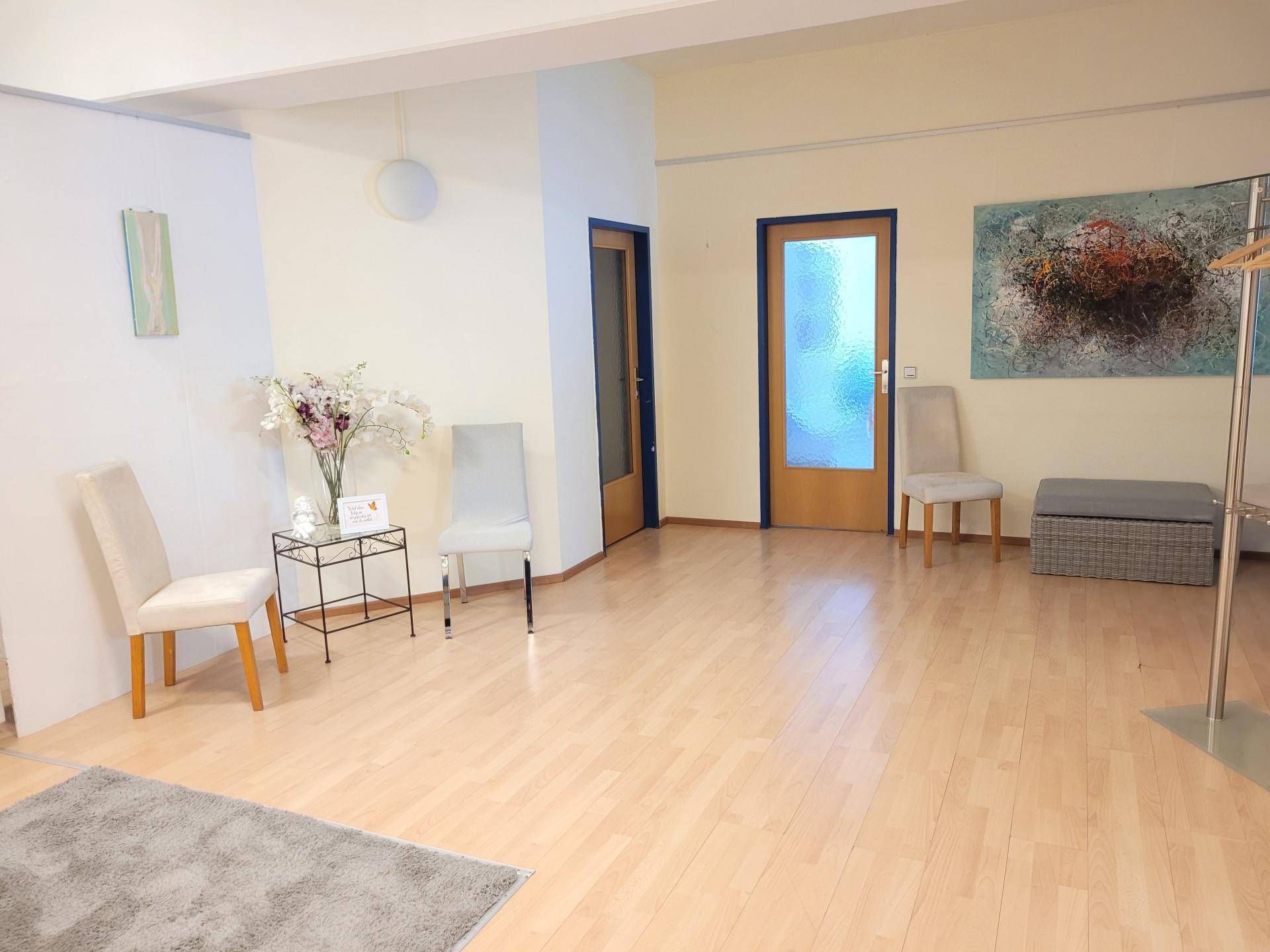 Geräumiger Empfangsbereich oder Büroraum mit hellem Holzboden und schlichten, modernen Möbeln.