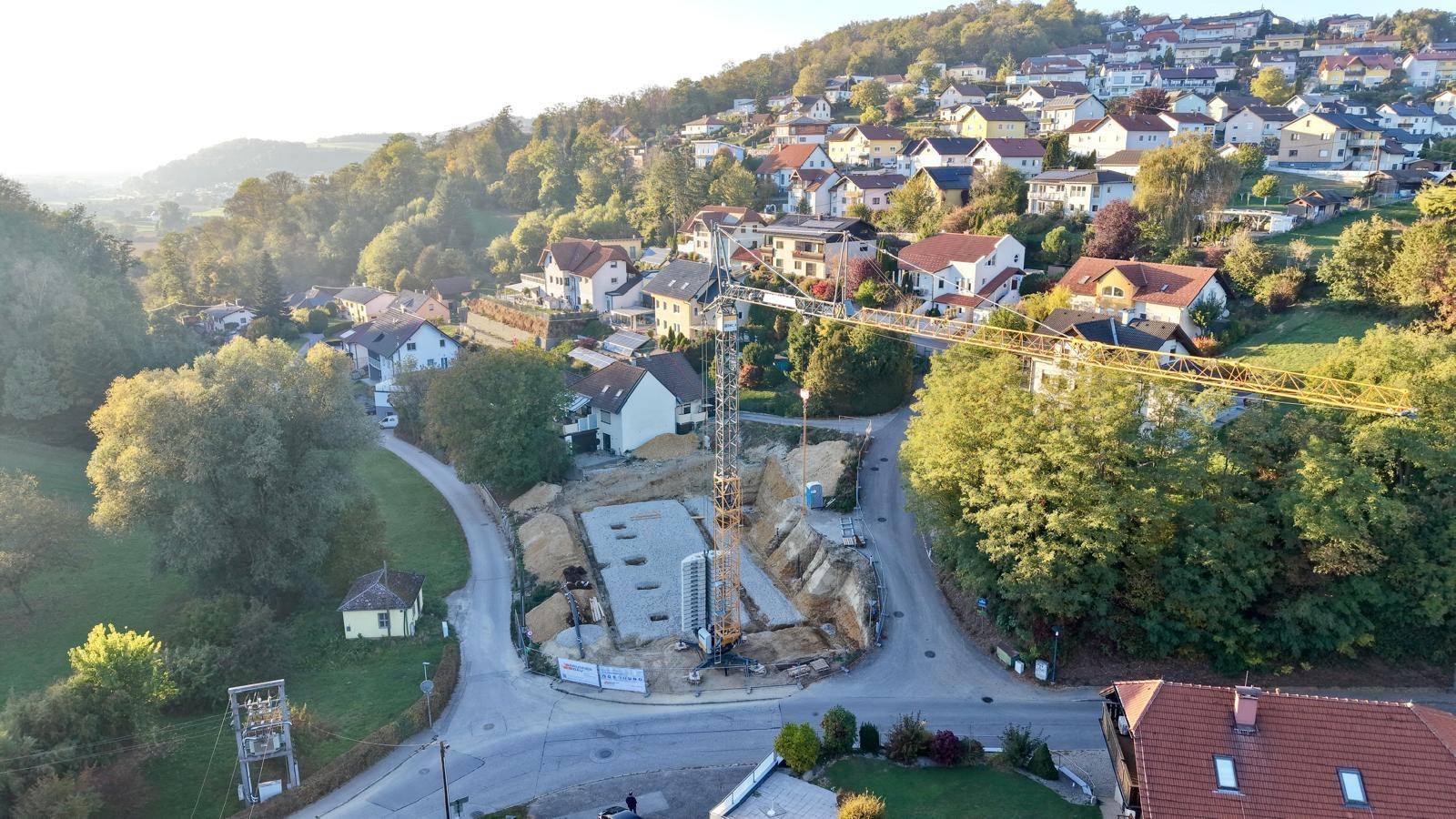 Luftaufnahme einer Baustelle für ein neues Gebäude in einer grünen Wohngegend.