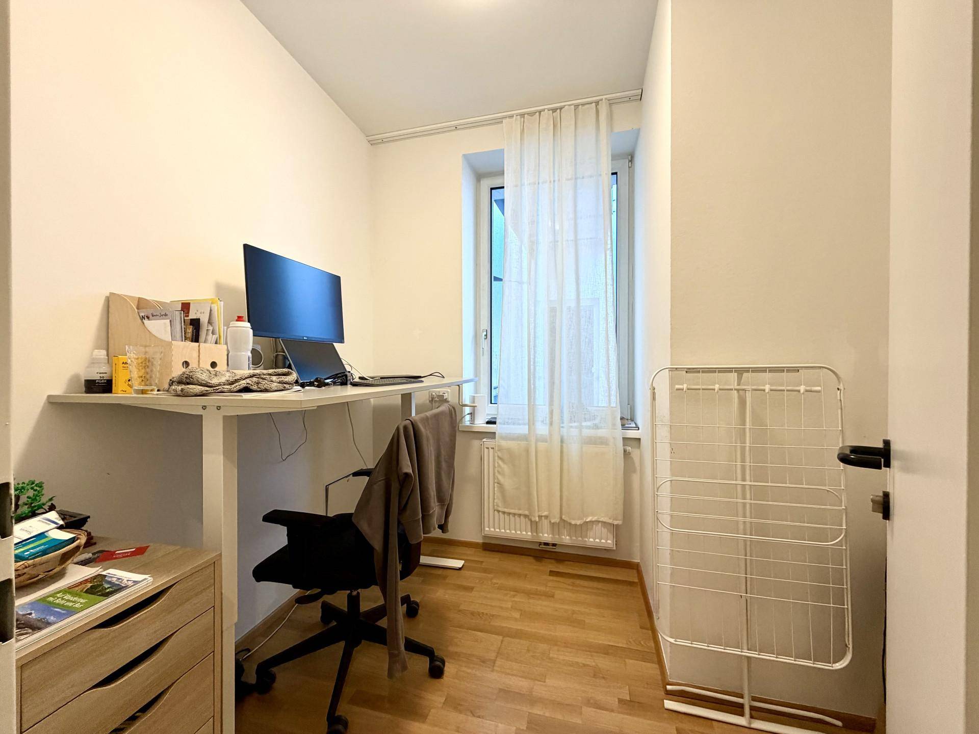 Funktionales Arbeitszimmer mit Schreibtisch, Fenster und Parkettboden.