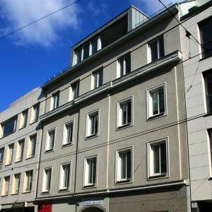 Mehrstöckiges Wohngebäude mit klassischer Fassade und vielen Fenstern unter blauem Himmel.