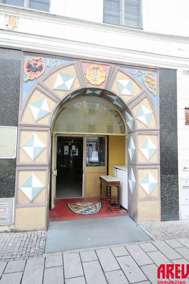 Historischer, reich verzierter Eingangsbereich mit bogenförmiger Tür und kleiner Rampe für Barrierefreiheit.