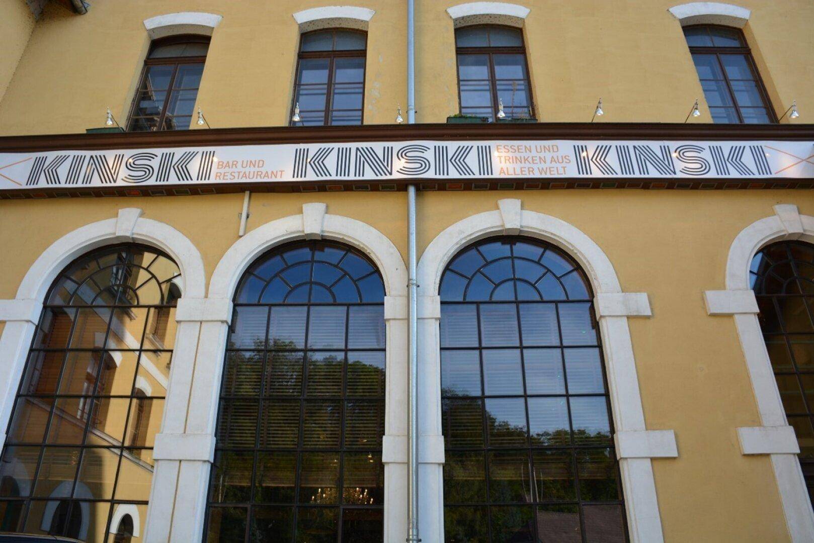 Detailansicht der gelben Fassade mit großen Bogenfenstern und dem "KINSKI" Schriftzug über den Eingängen.