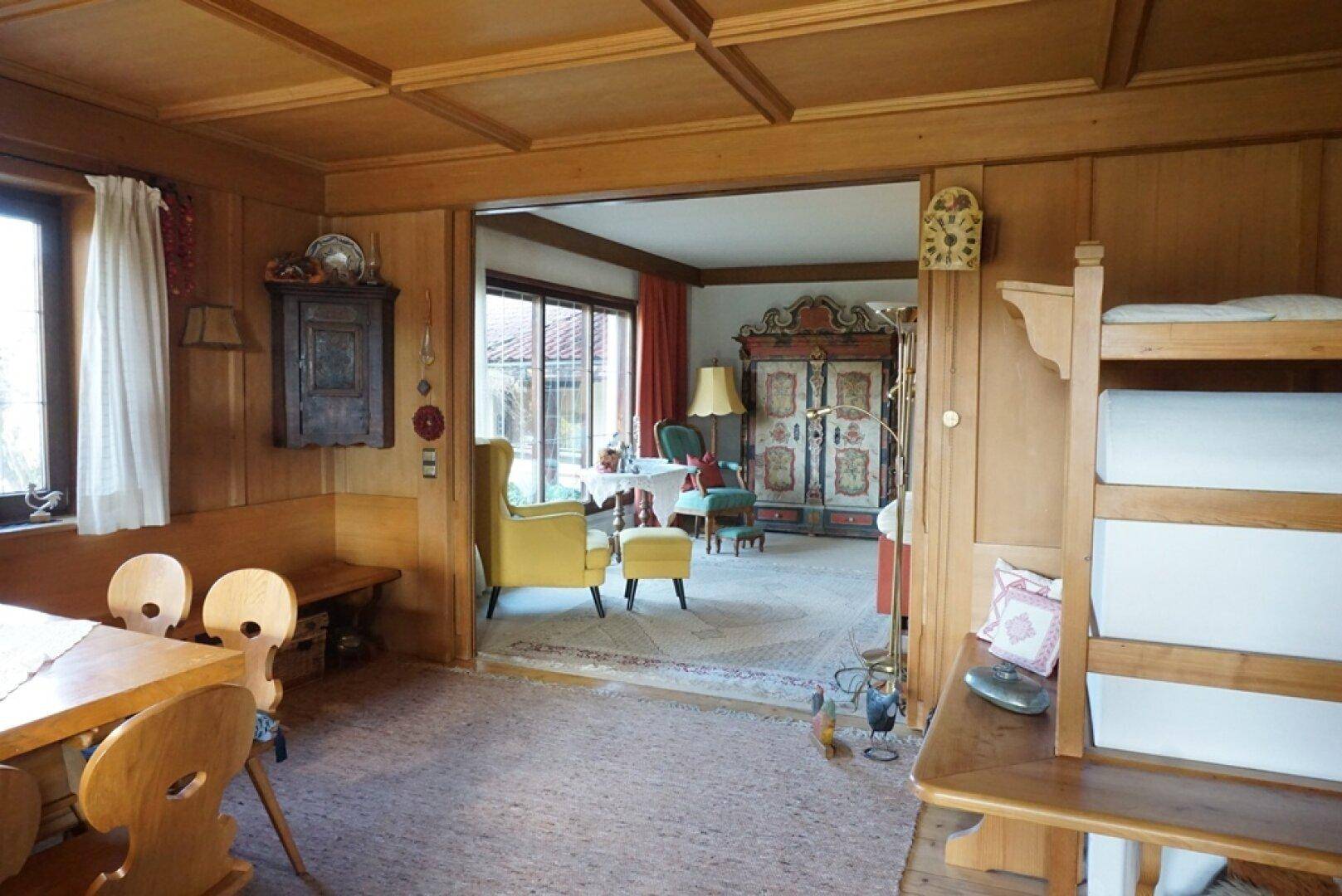 Rustikaler Essbereich mit Holzvertäfelung und Kassettendecke, offen zum Wohnzimmer.