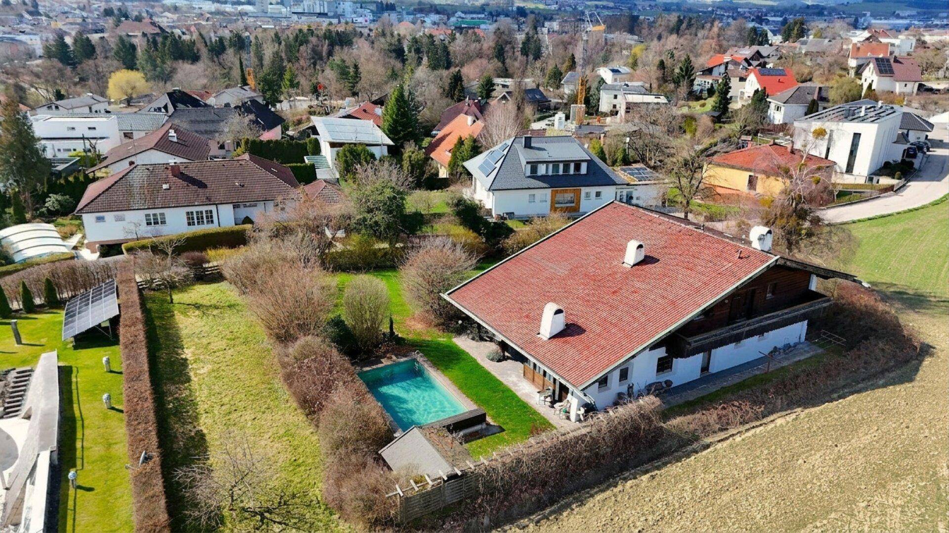 Luftaufnahme des Anwesens mit Haus, Garten, Pool und umliegender Wohnsiedlung.