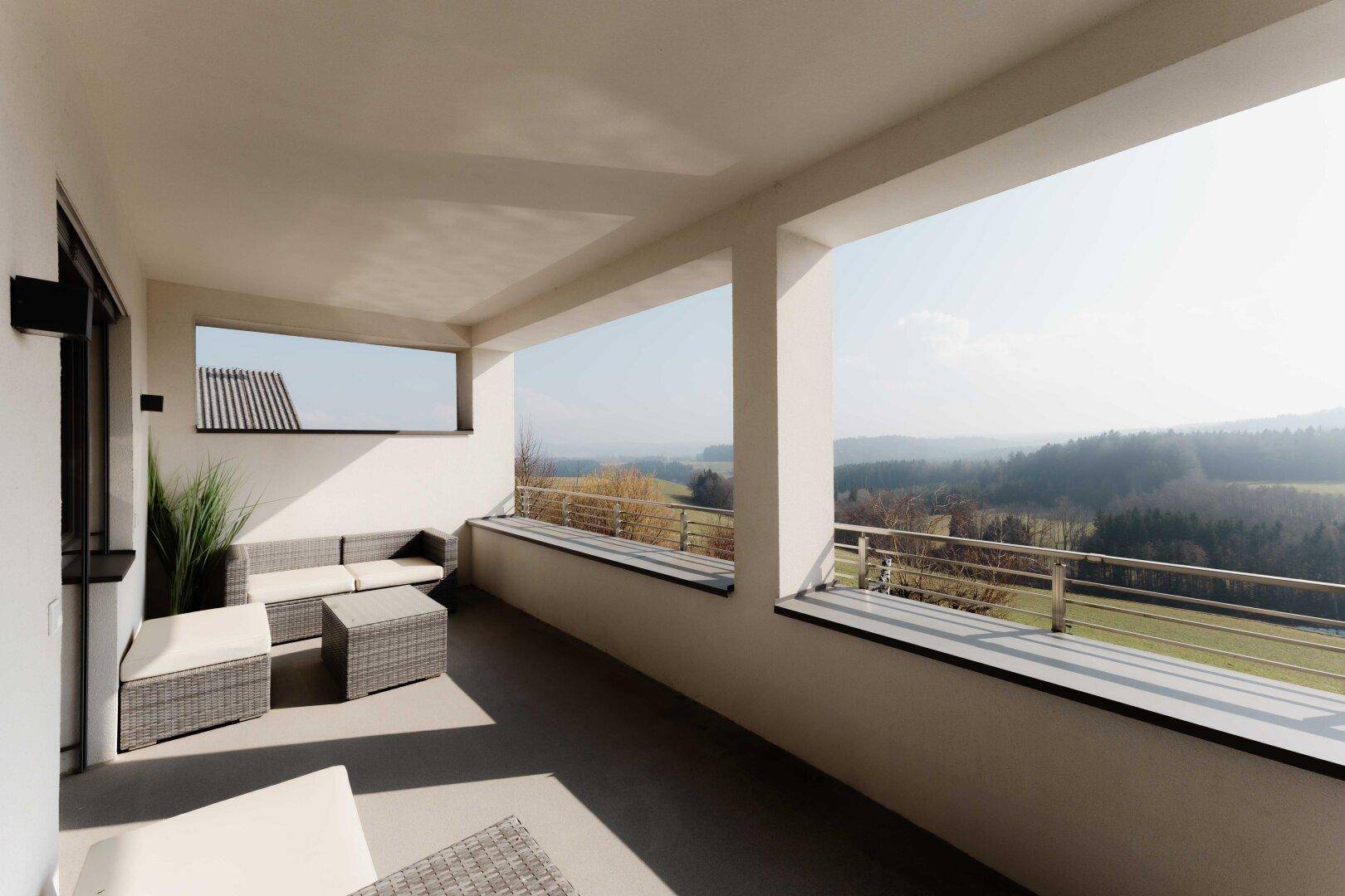 Geräumiger Balkon mit bequemen Loungemöbeln und weitem Blick über die grüne Landschaft.
