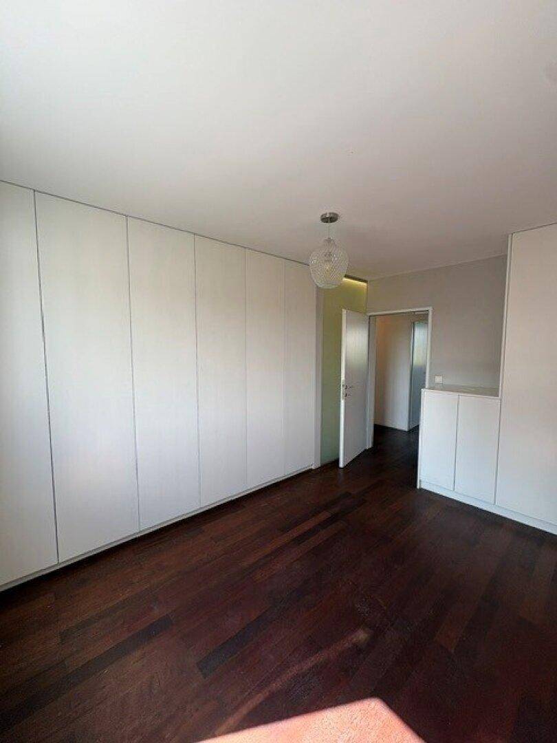 Geräumiges Schlafzimmer mit durchgehenden Einbauschränken und dunklem Parkettboden.