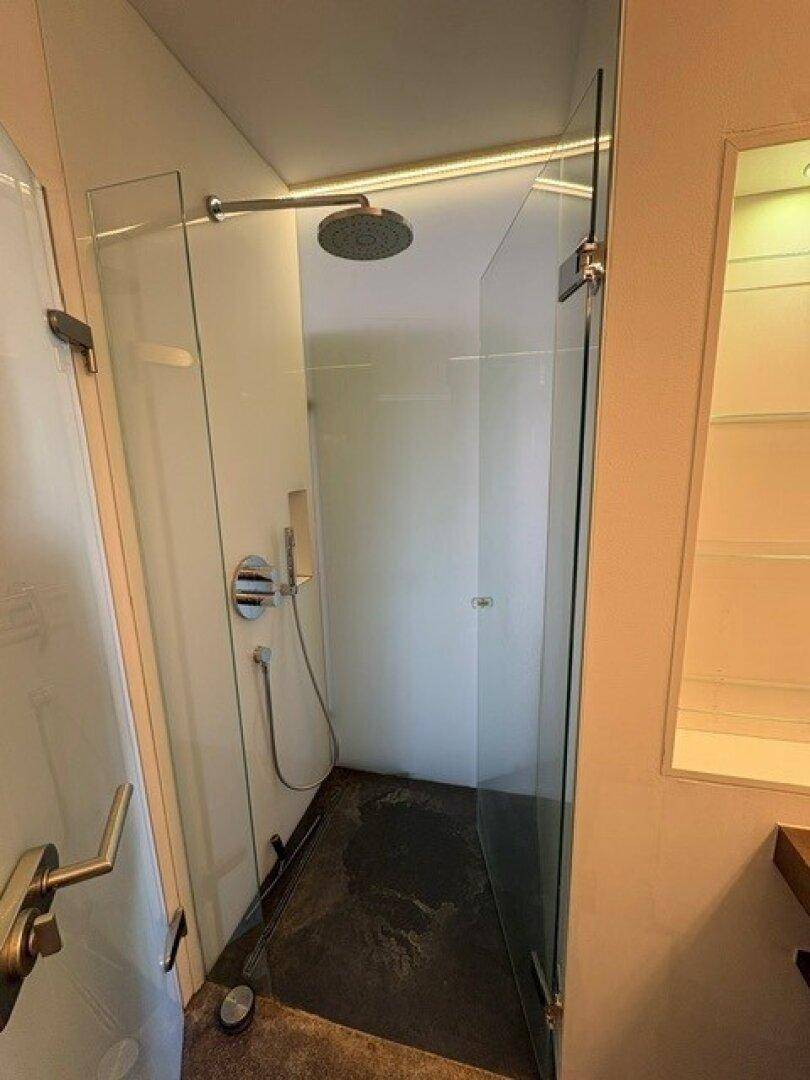 Moderne Duschkabine mit Glaswänden und Regendusche, minimalistisch gestaltet.